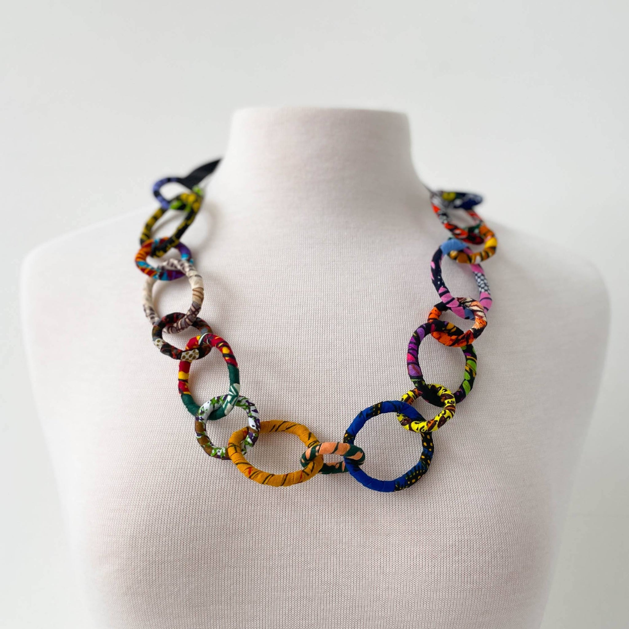Colorful chain necklace on a mannequin bust against a white background