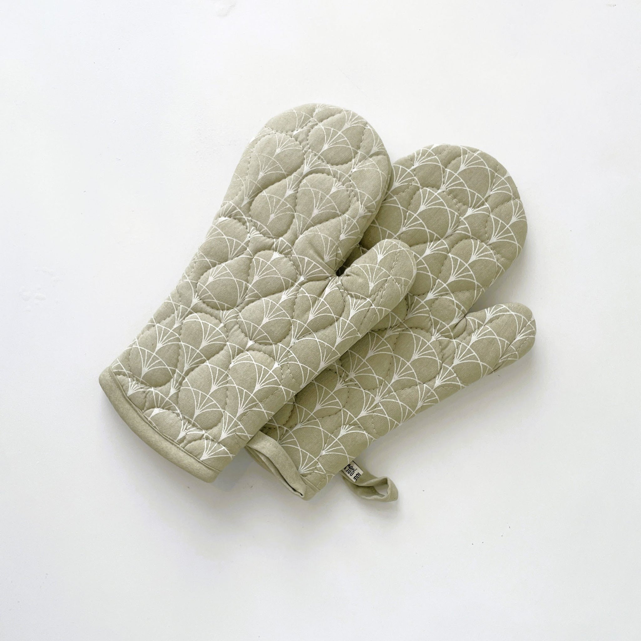 Pair of green quilted oven mitts on a white background