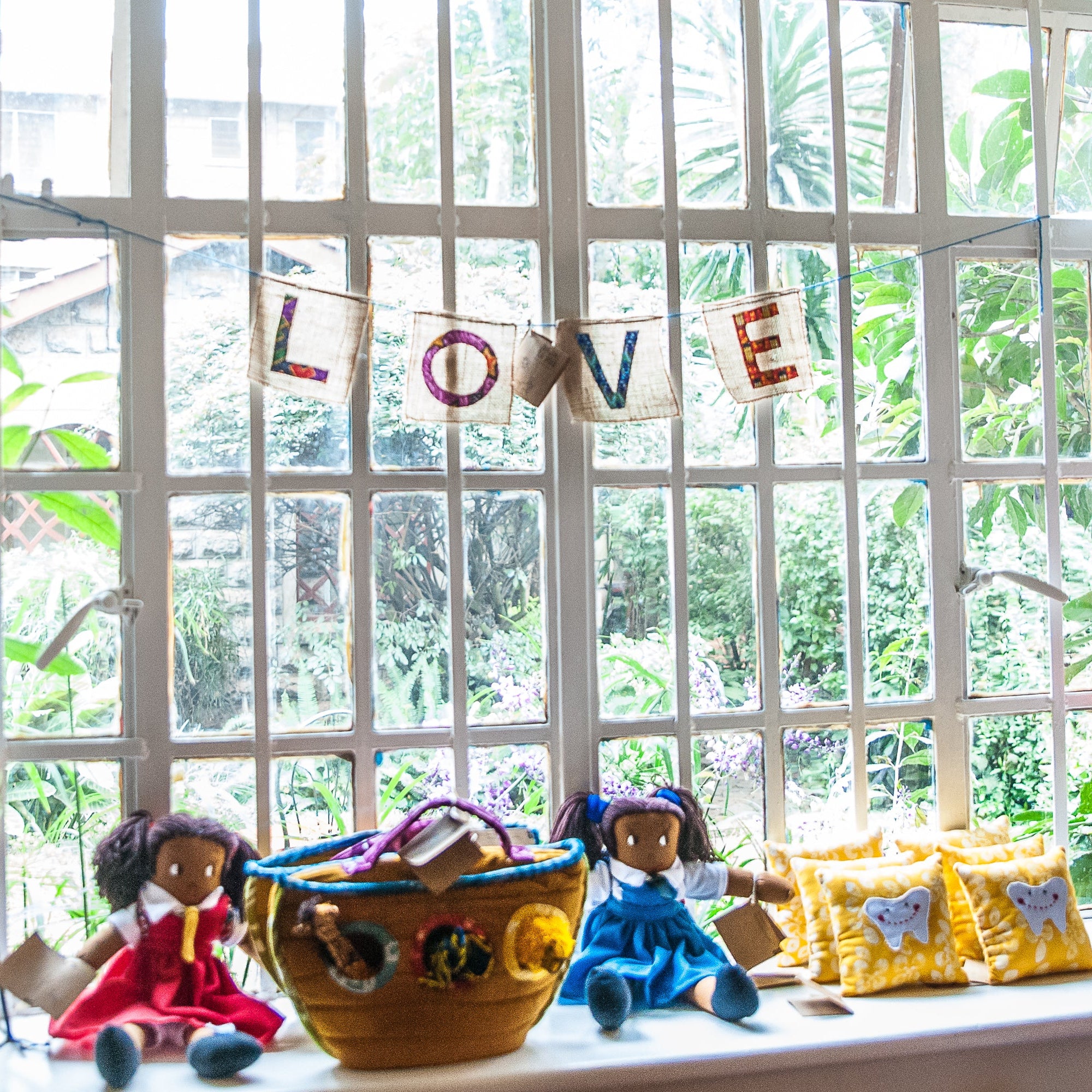 Children's toys and decorations on a windowsill with 'LOVE' banner