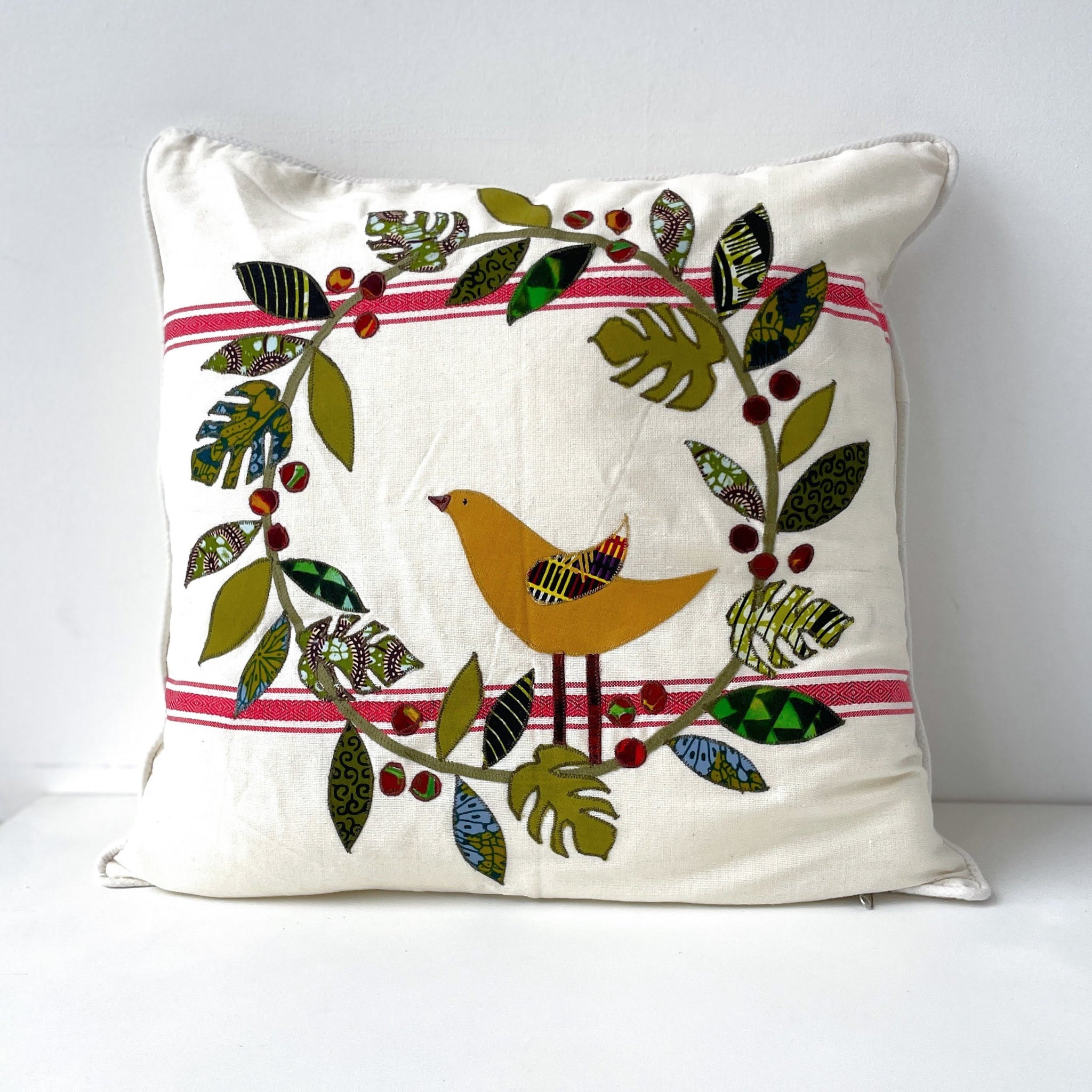 Decorative pillow with a bird and leaf design on a white background