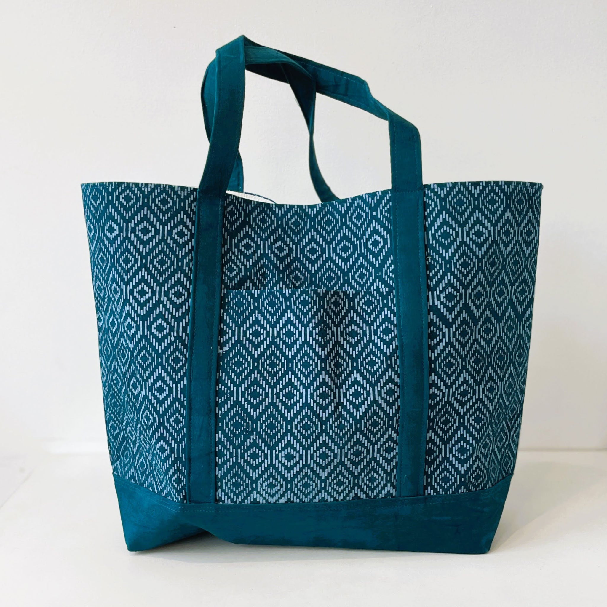 Teal tote bag with a geometric pattern on a white background