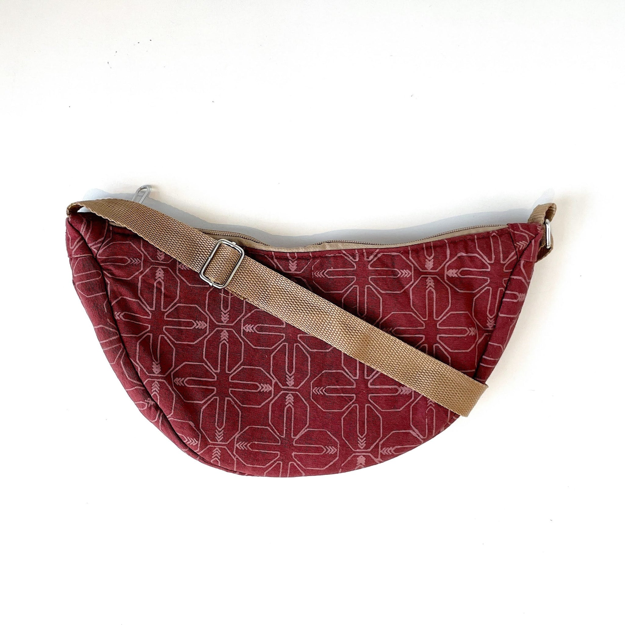 Red patterned bag with a brown strap on a white background