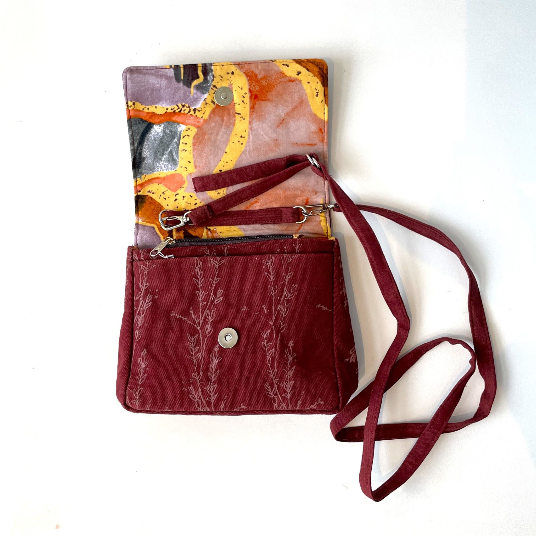 Red crossbody bag with floral pattern on a white background