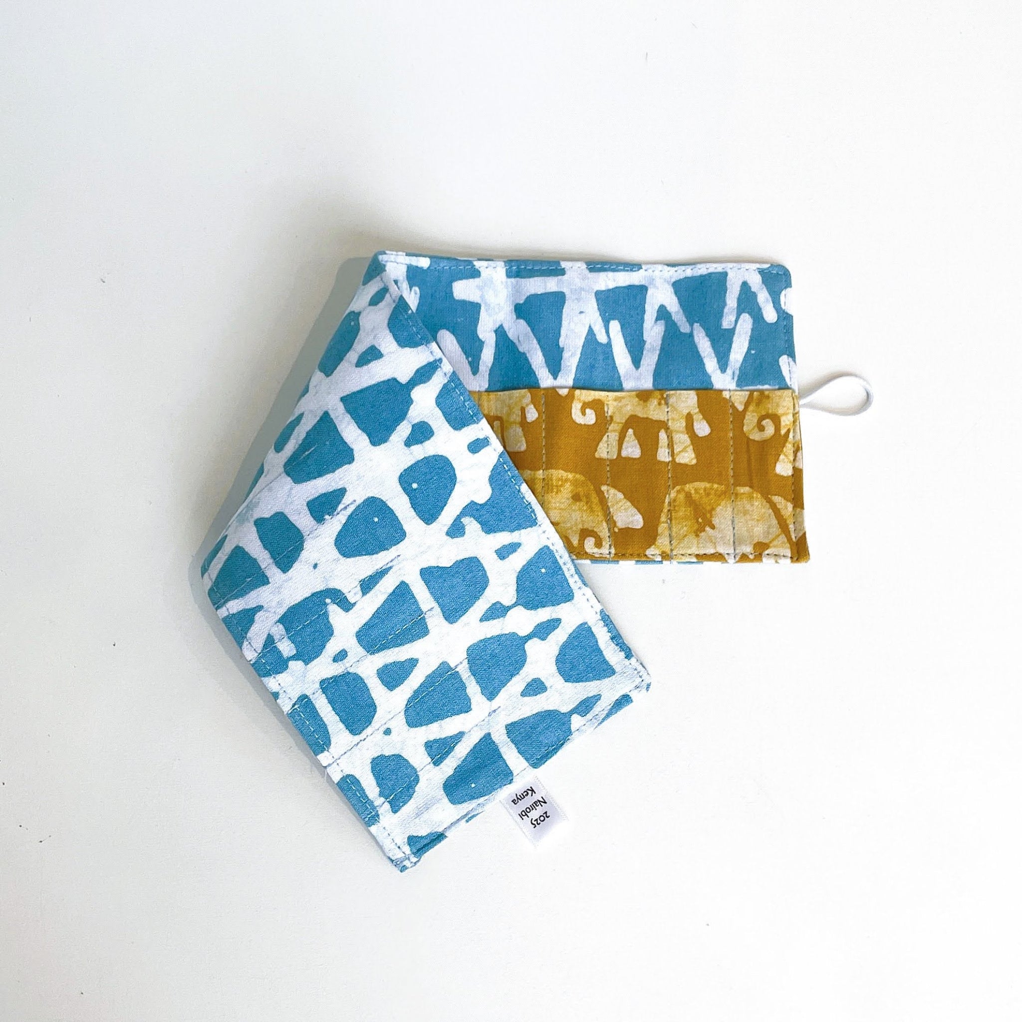 Two fabric pouches with blue and white patterns and mustard yellow pattern on a white background