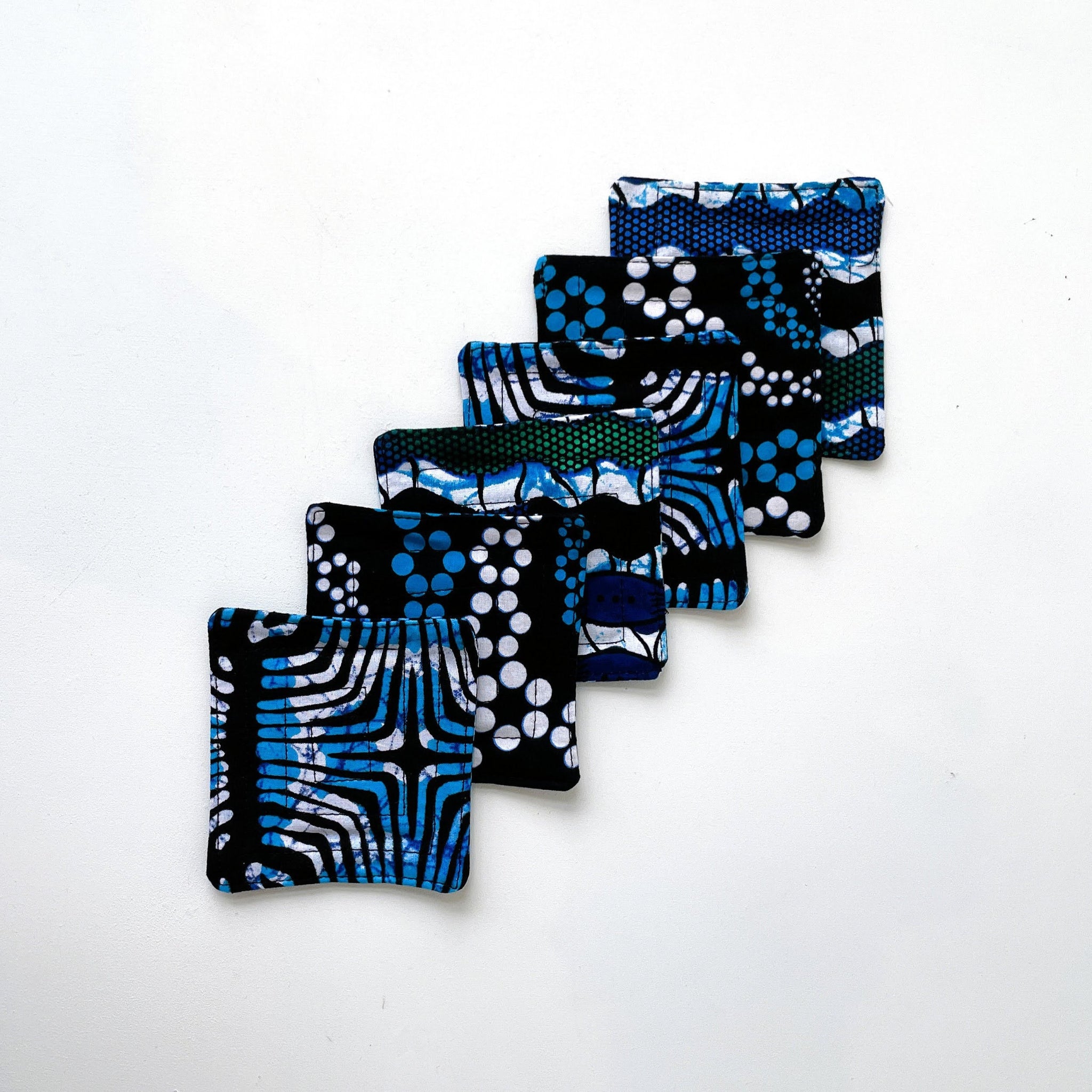 Set of blue and black patterned square coasters on a white background