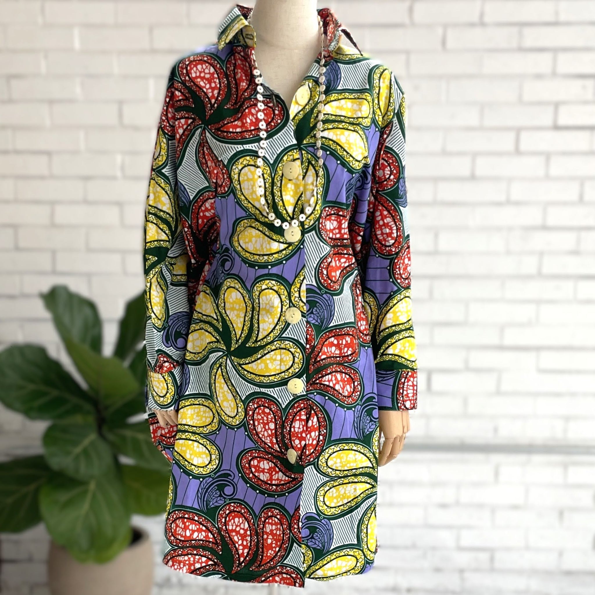 Colorful floral dress on a mannequin against a white brick wall.