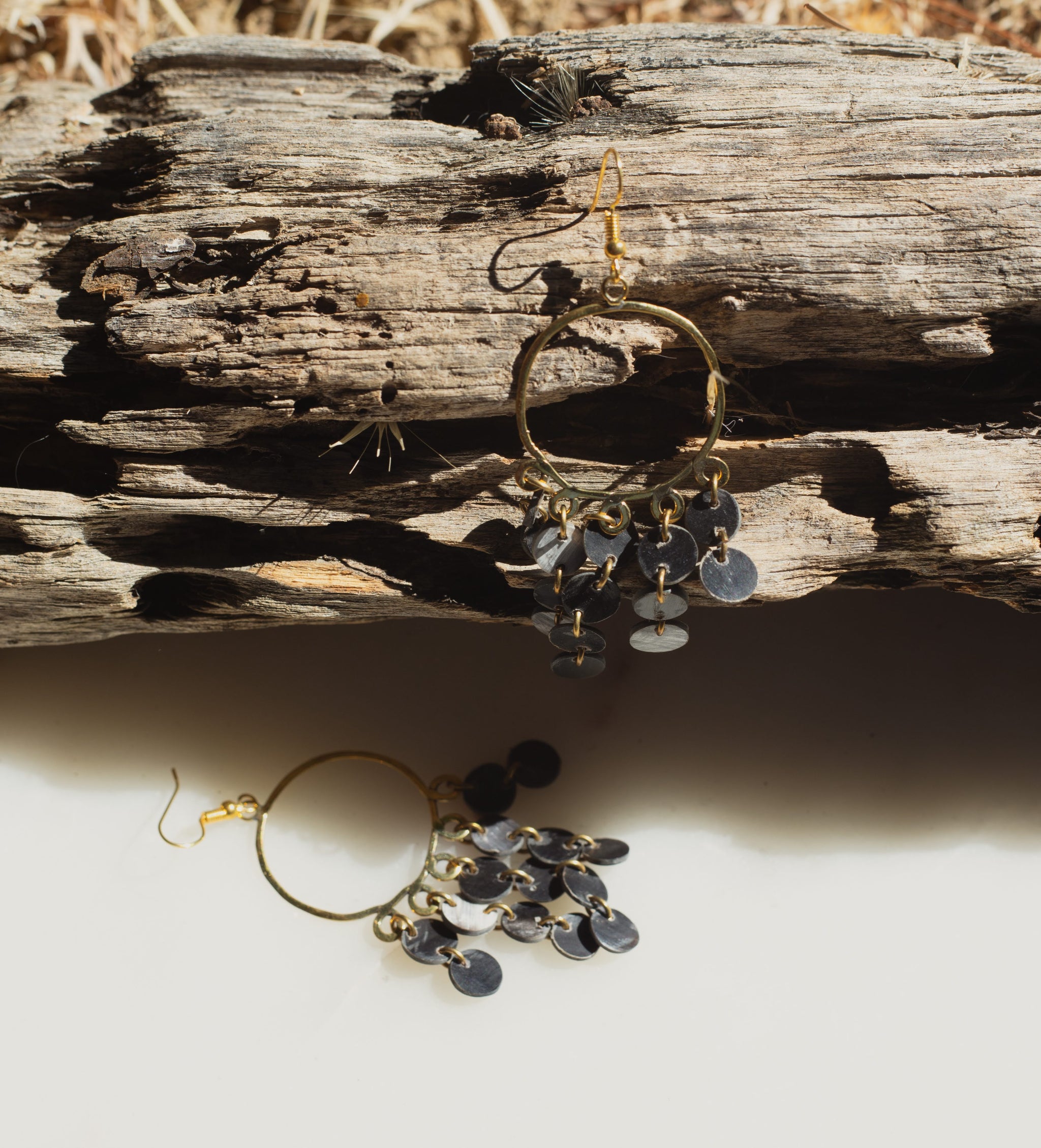 Brass hoop earrings with dangling charms on a wooden surface