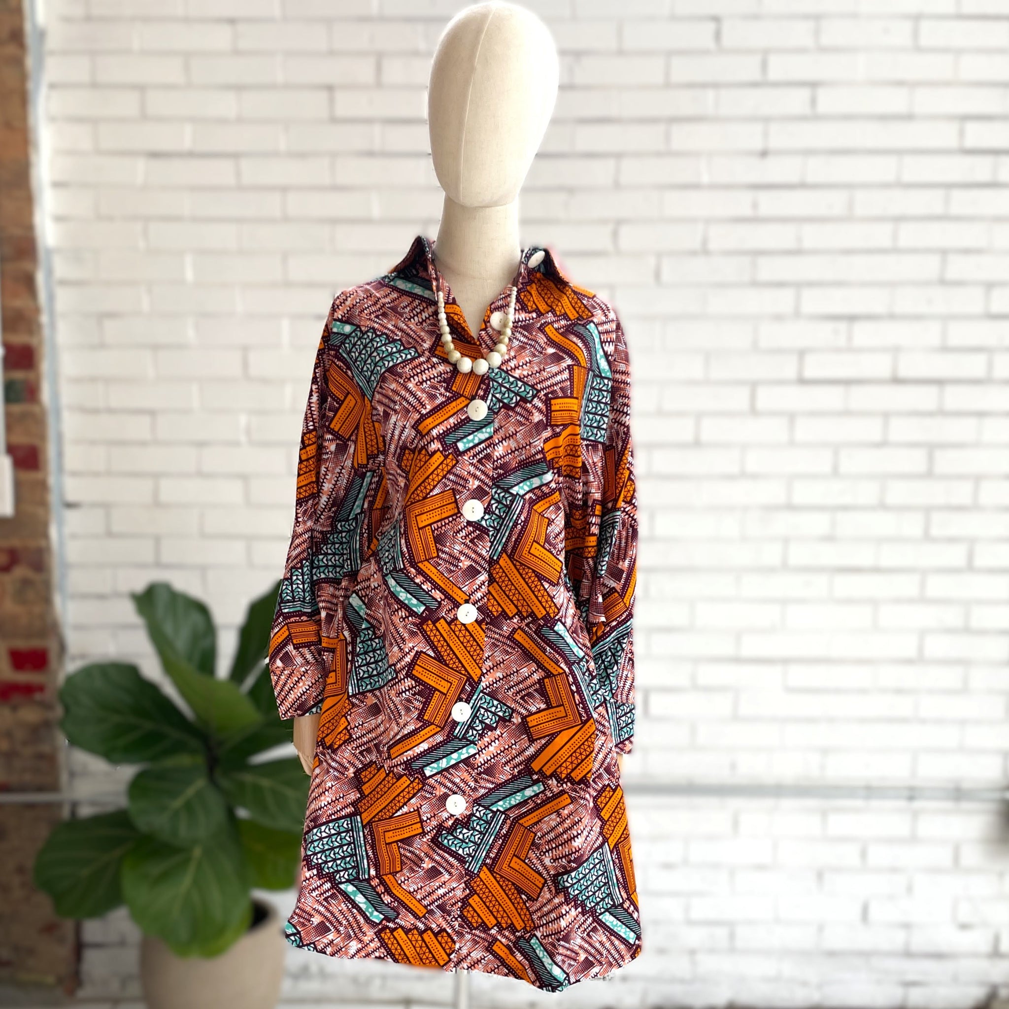 Mannequin wearing a patterned dress with a white brick wall background