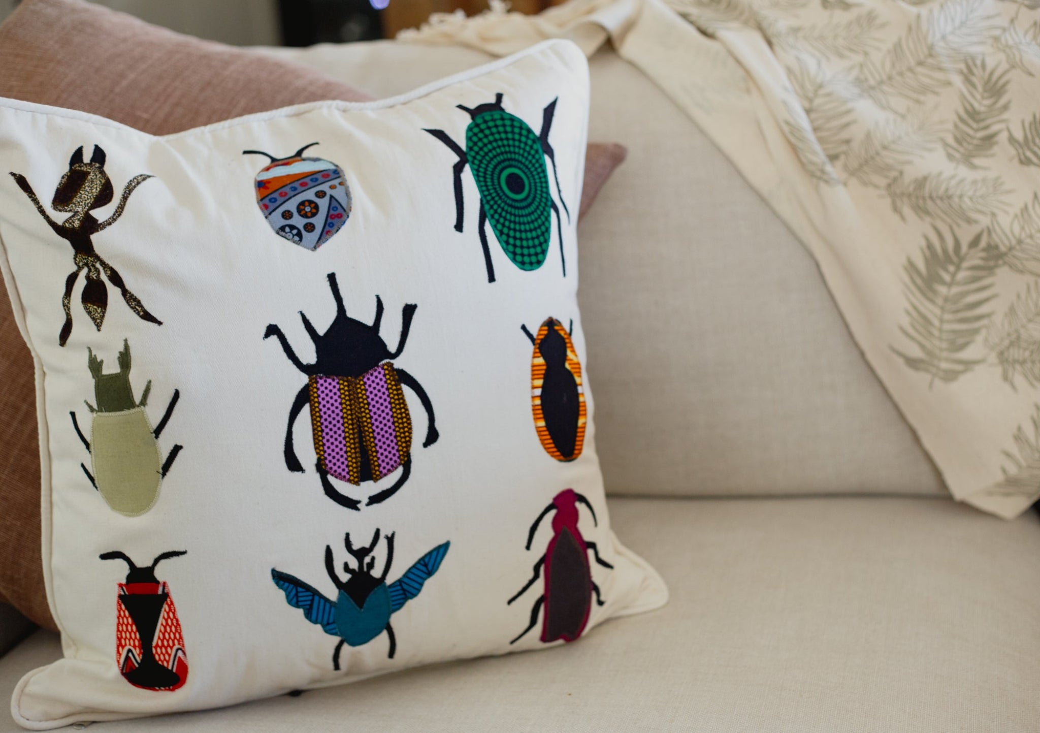 Decorative pillow with embroidered beetle designs on a couch.