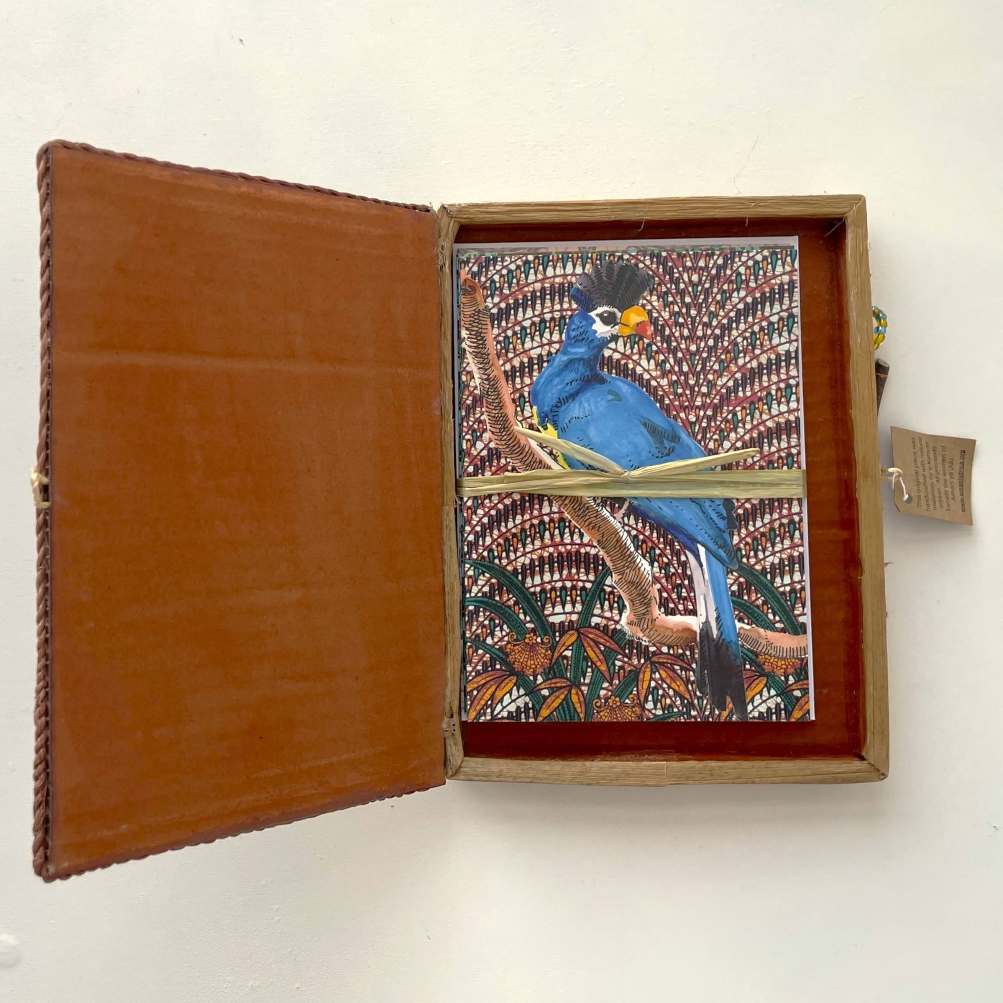 Open banana leaf box with a colorful bird illustration on a white background
