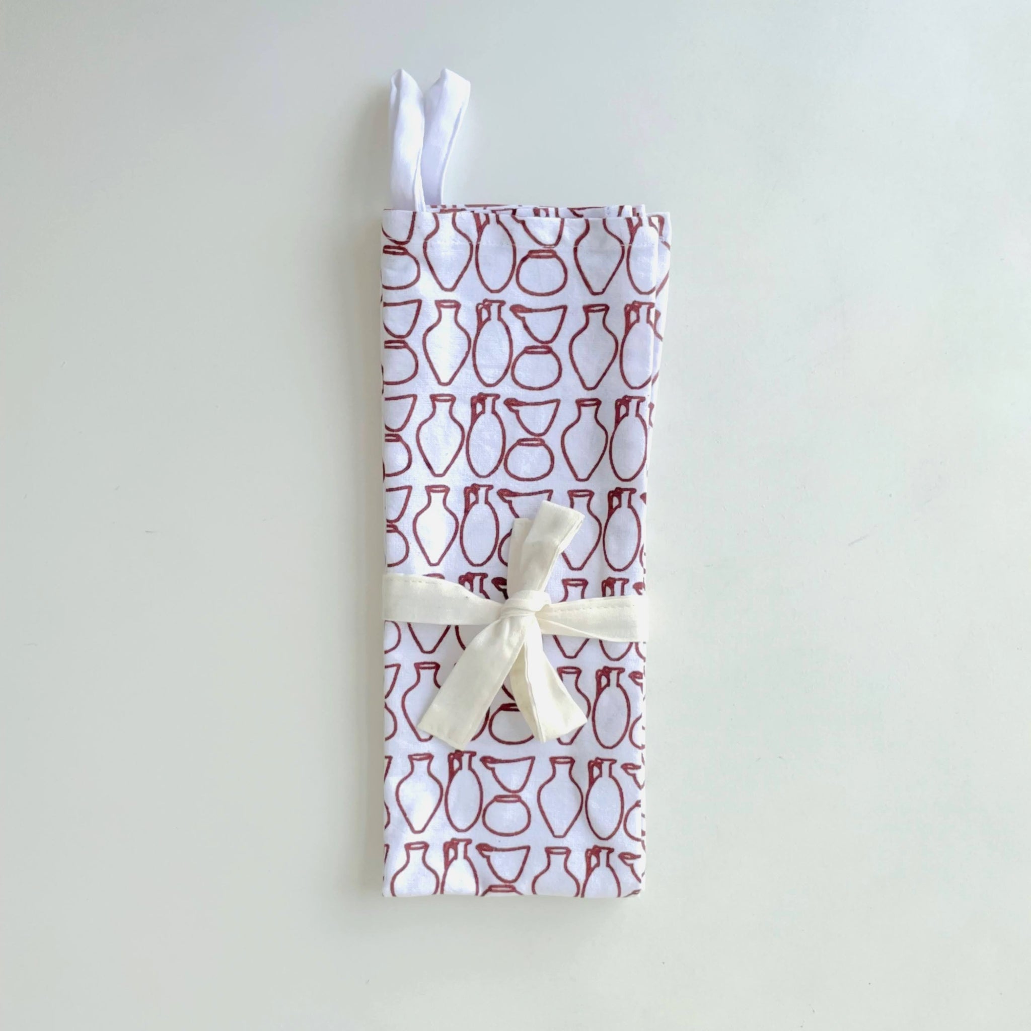 Folded fabric with red and white pottery pattern on a light gray background