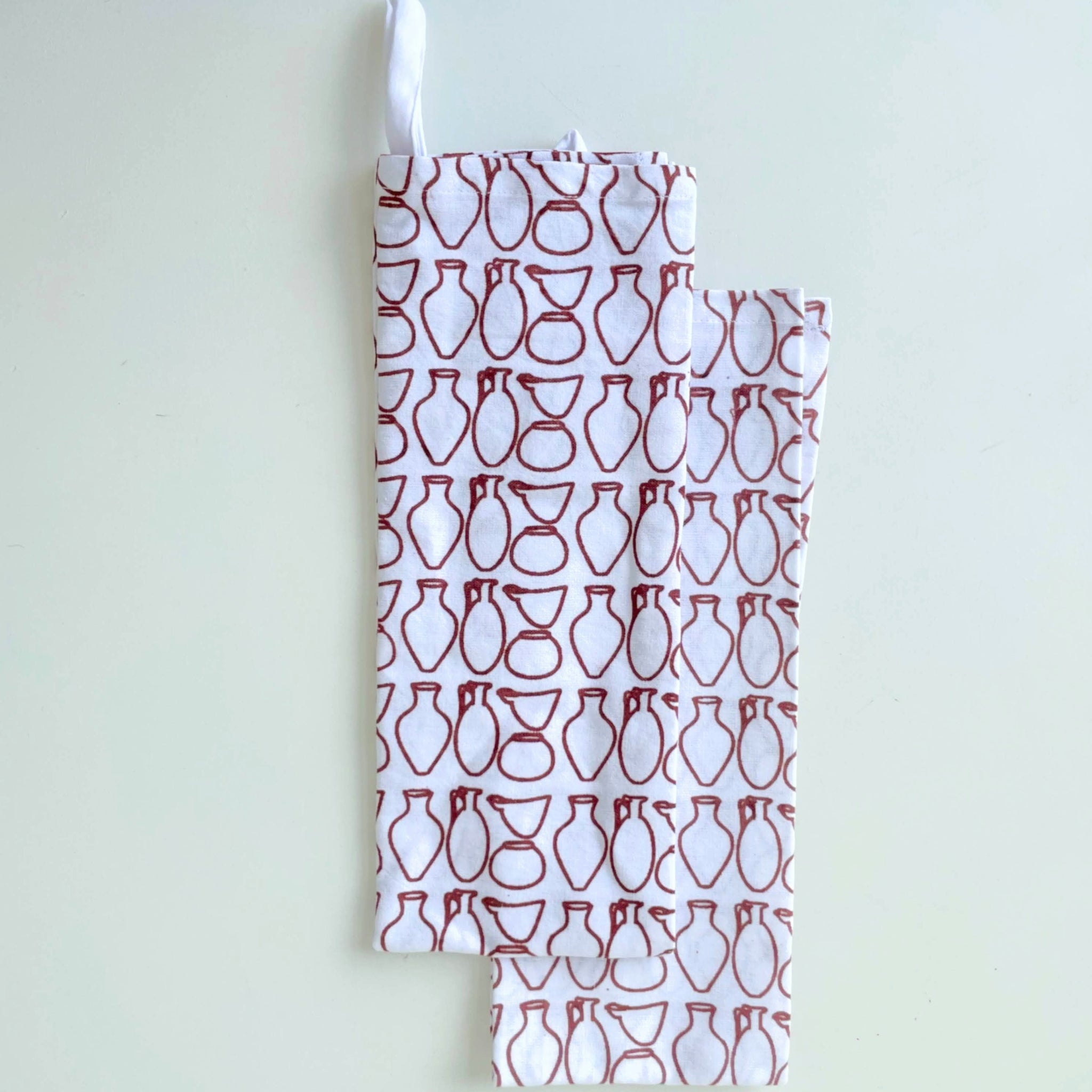 Towel with red and white pottery pattern on a light gray background