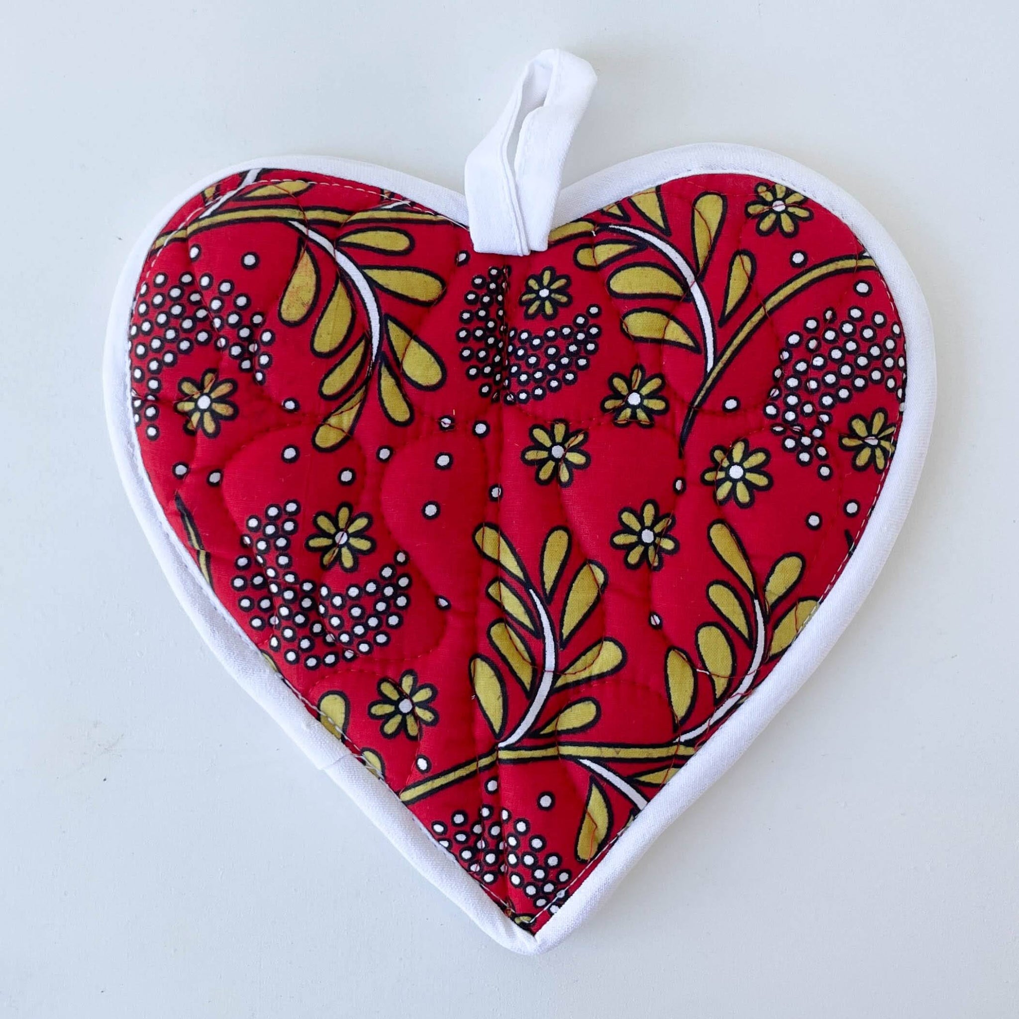 Heart-shaped pot holder with red floral pattern on a white background
