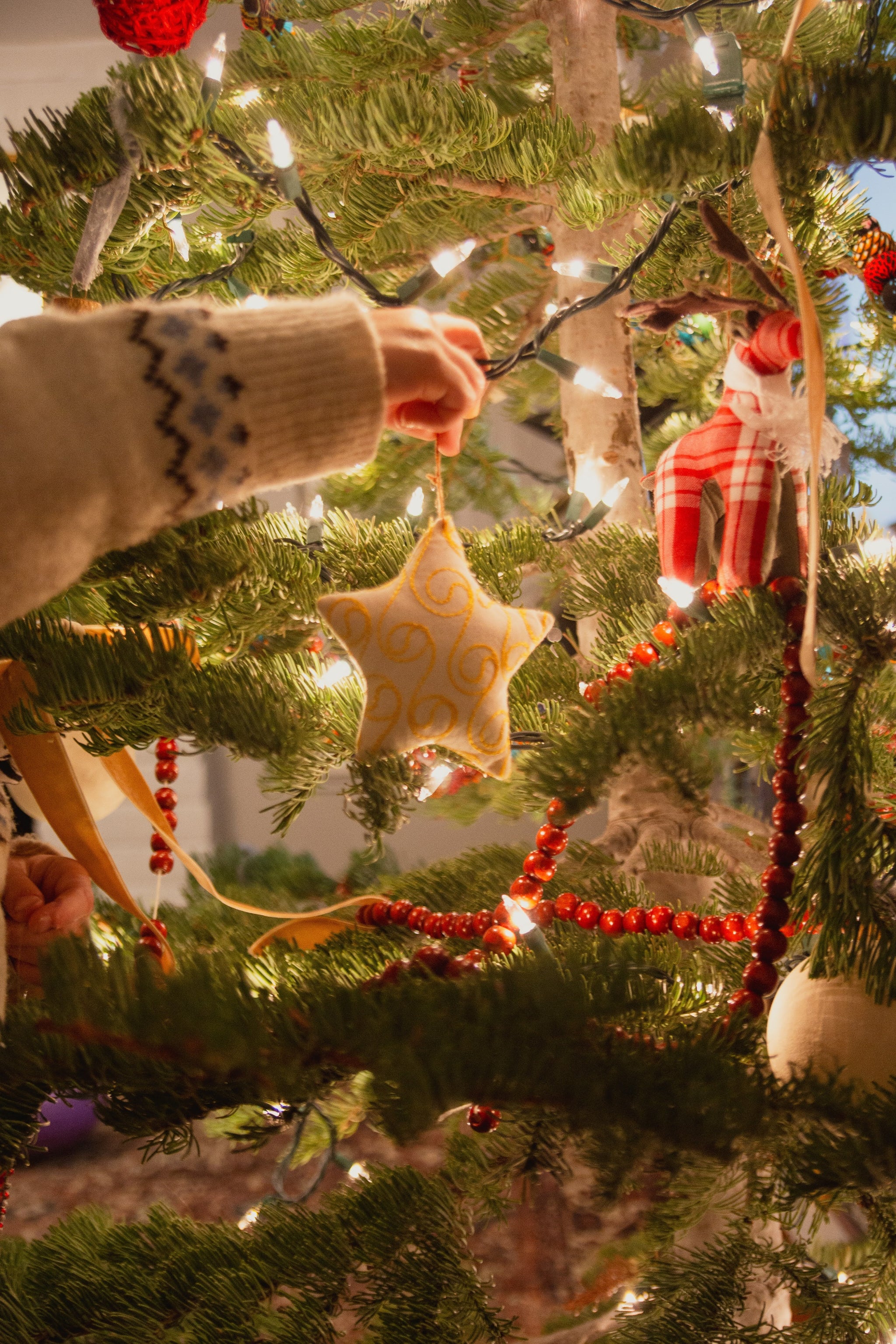 Person decorating a Christmas tree with ornaments and lights