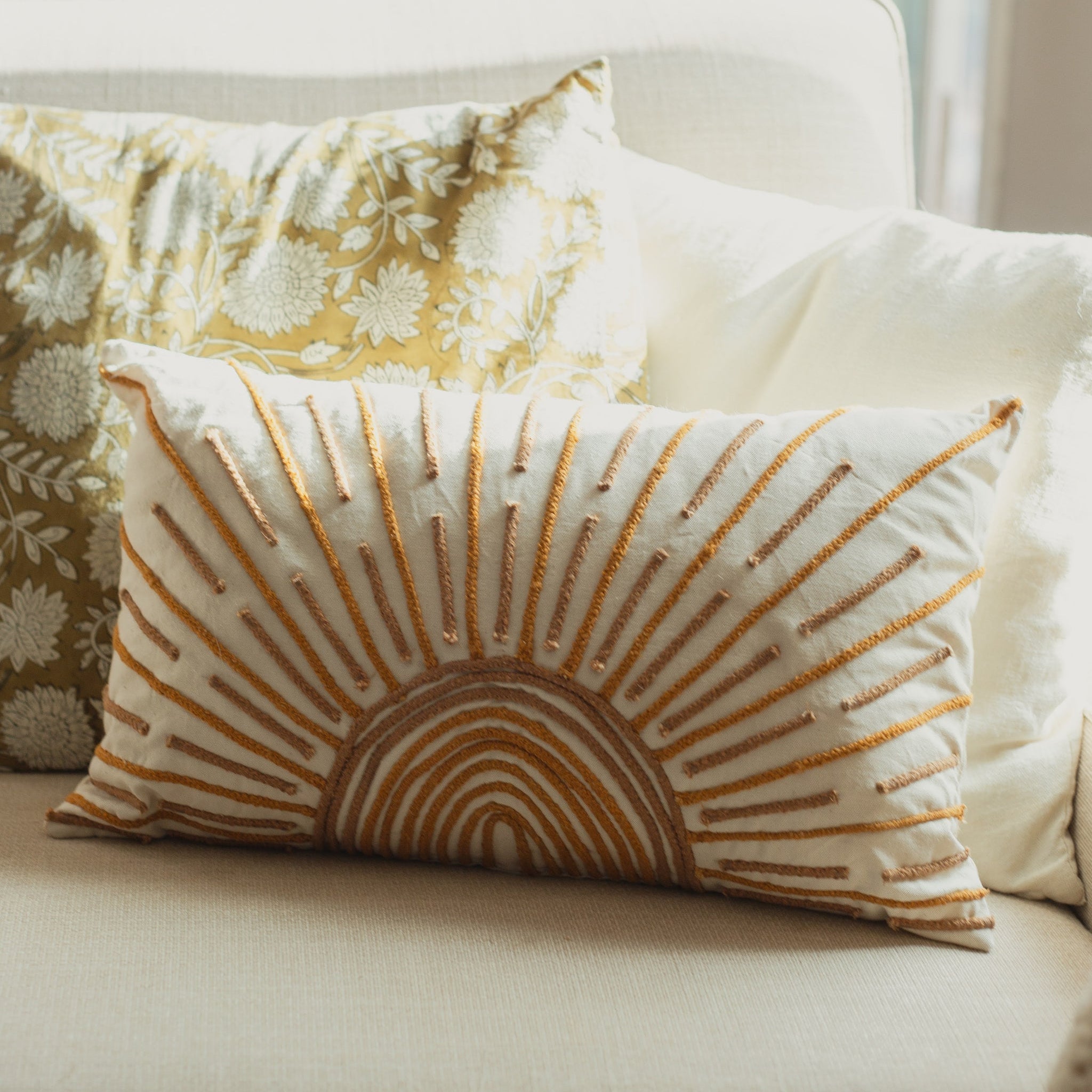 Decorative pillows on a sofa with a sunburst pattern and floral design.