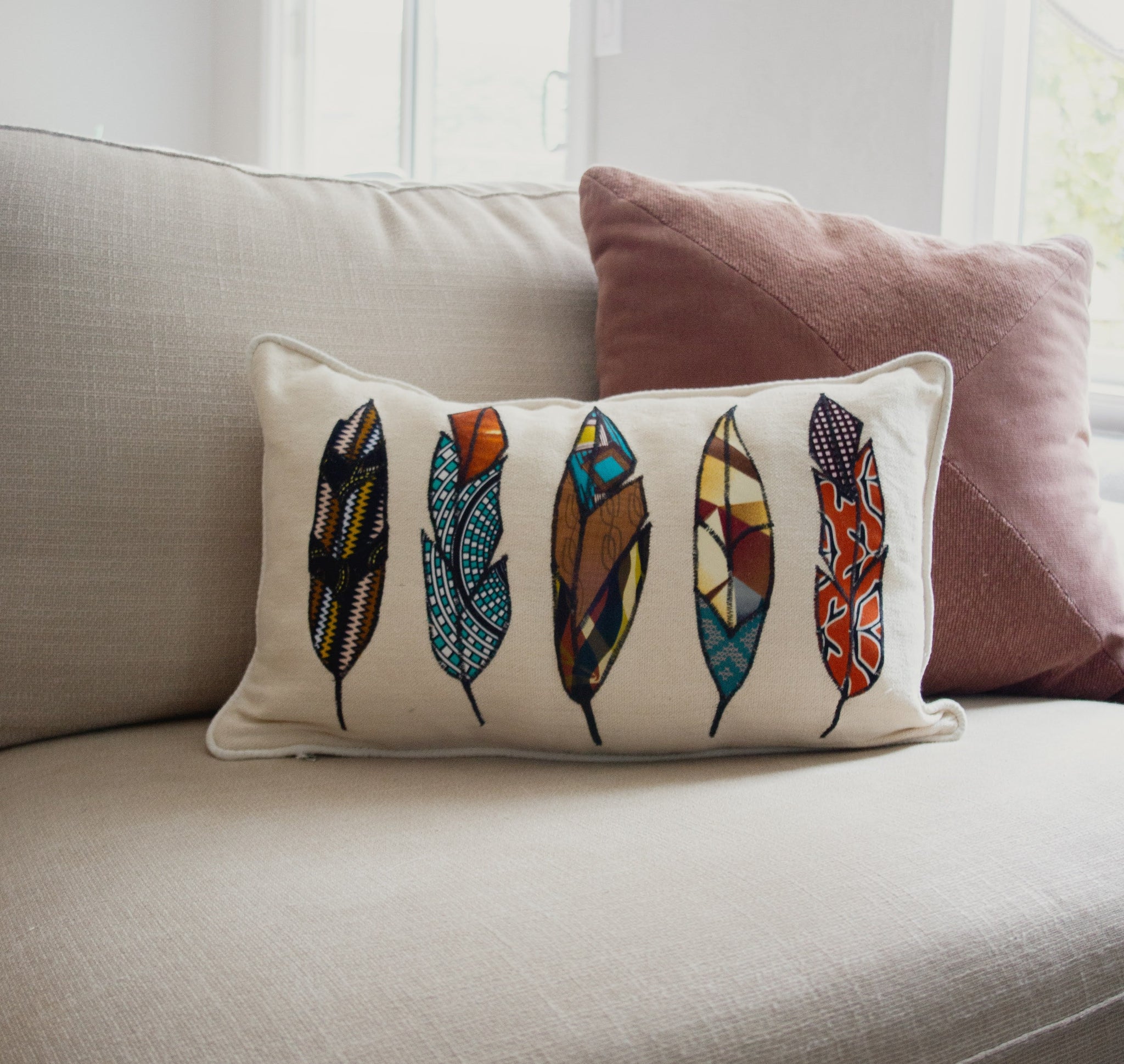 Decorative pillow with feather design on a beige couch