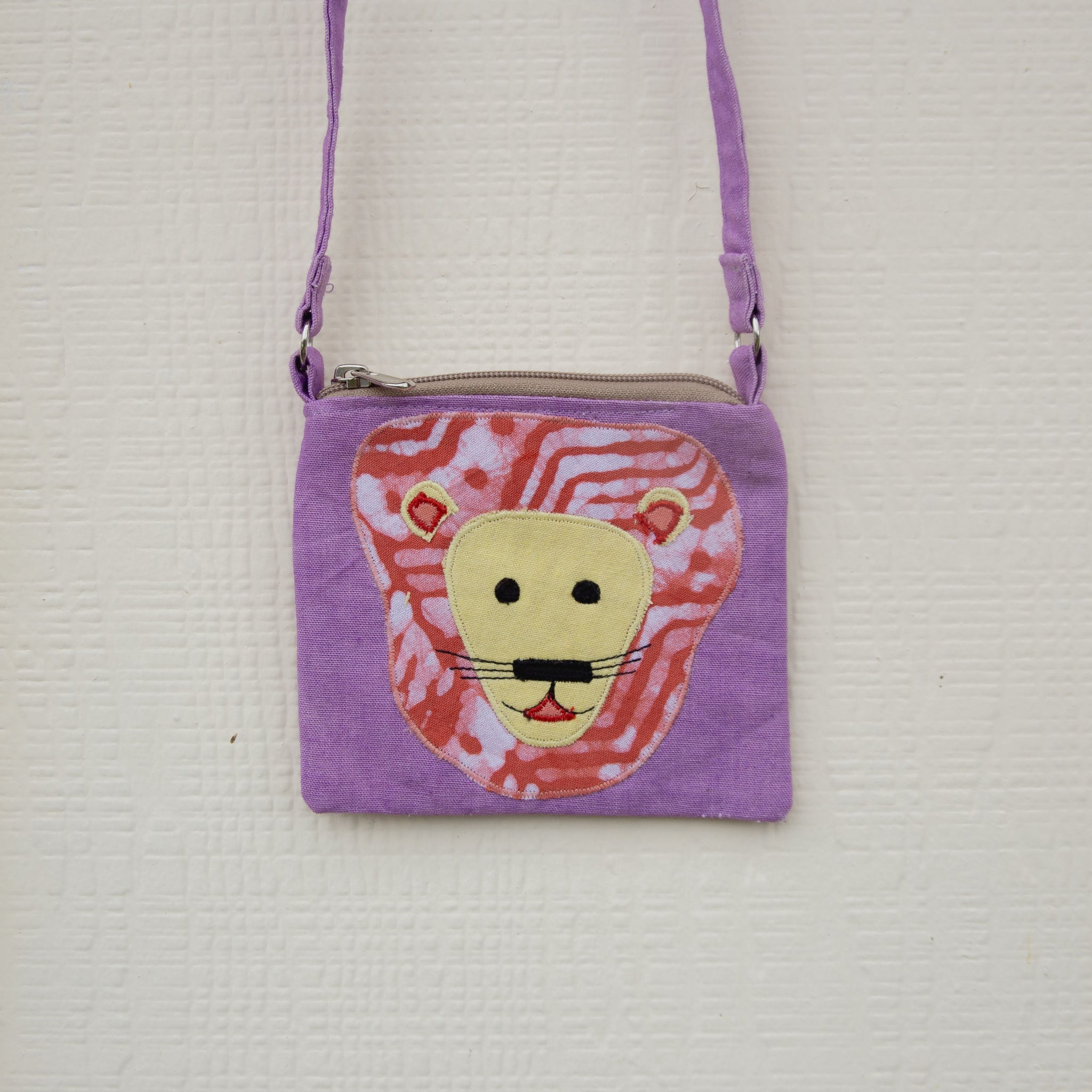 Purple children's bag with a lion face design on a textured white background