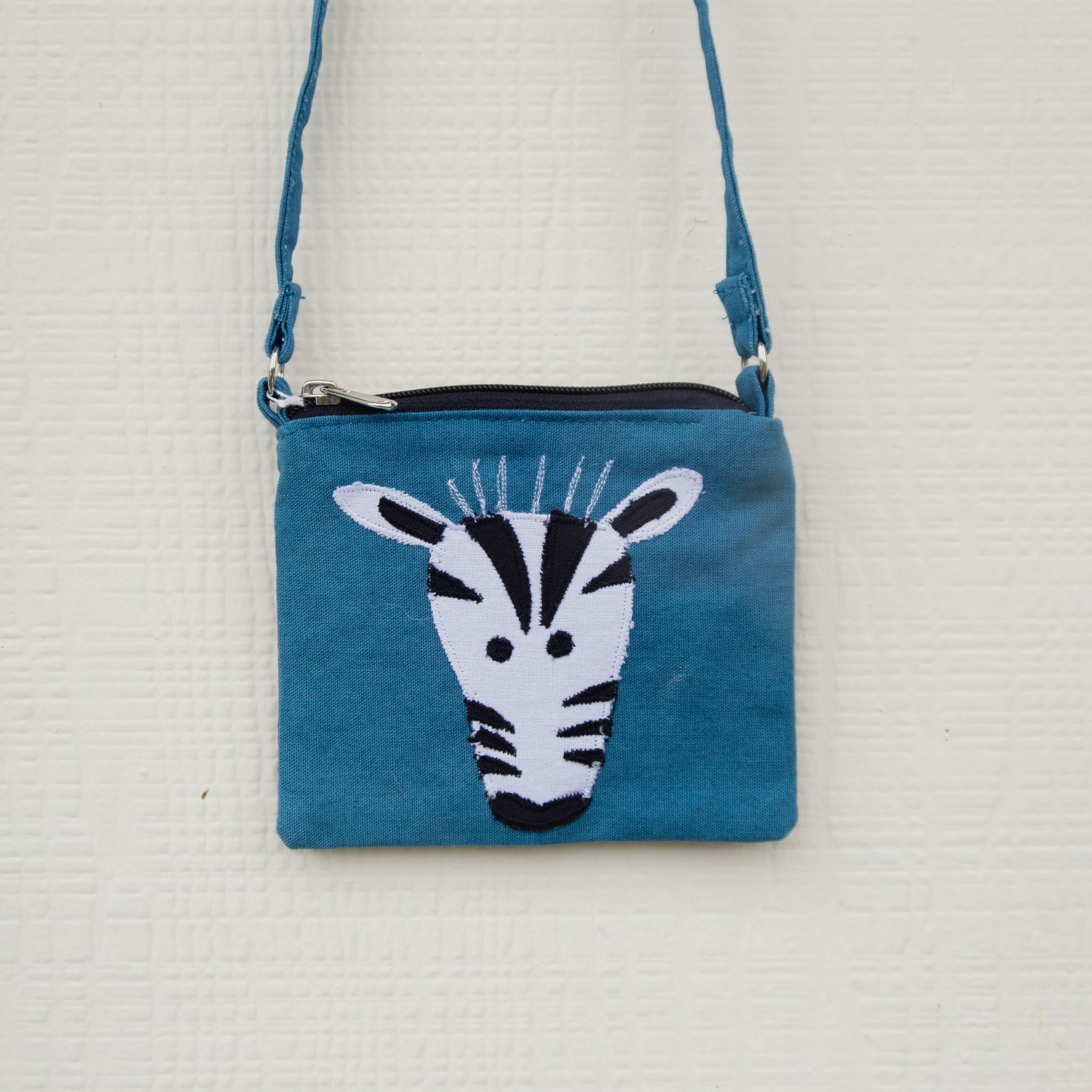 Blue crossbody bag with a zebra design on a white background
