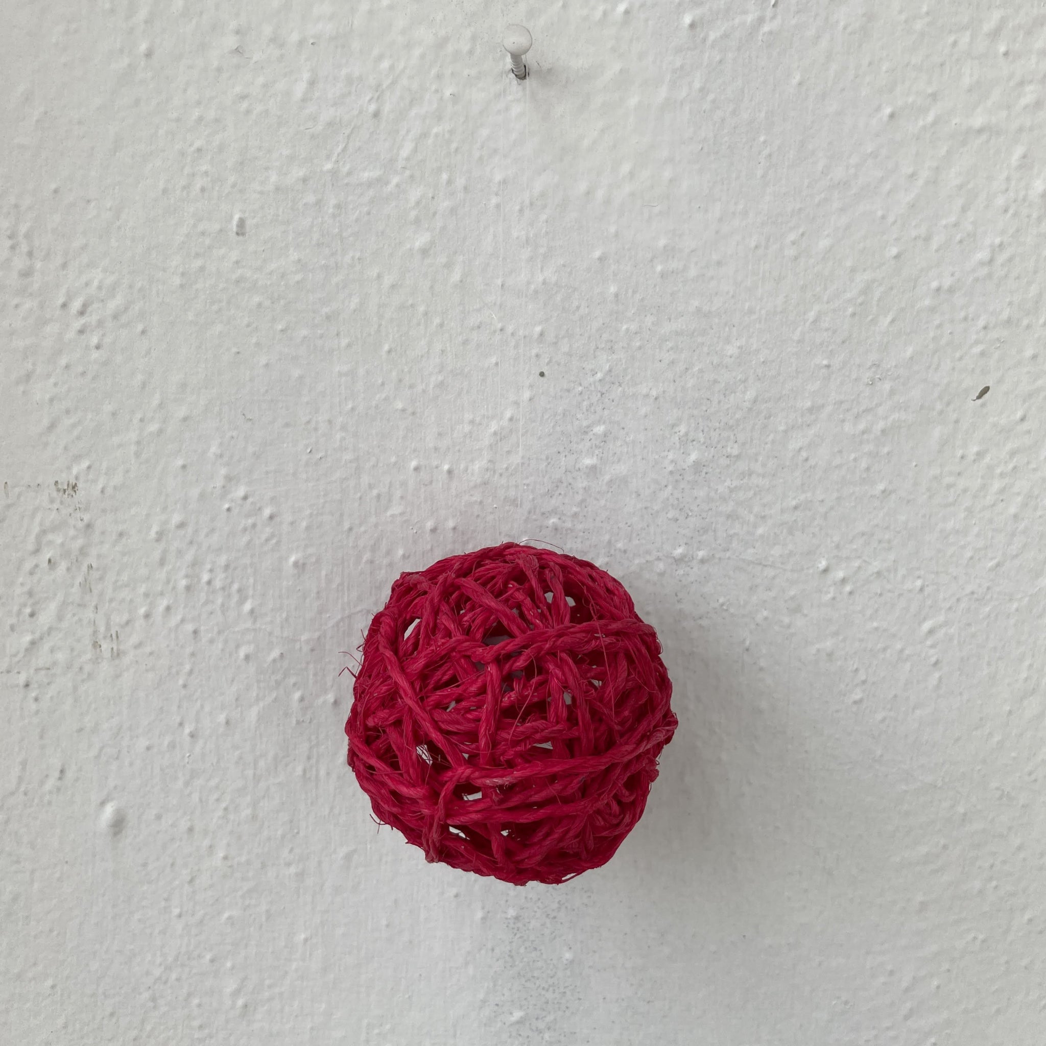 Red woven ball on a light gray textured surface