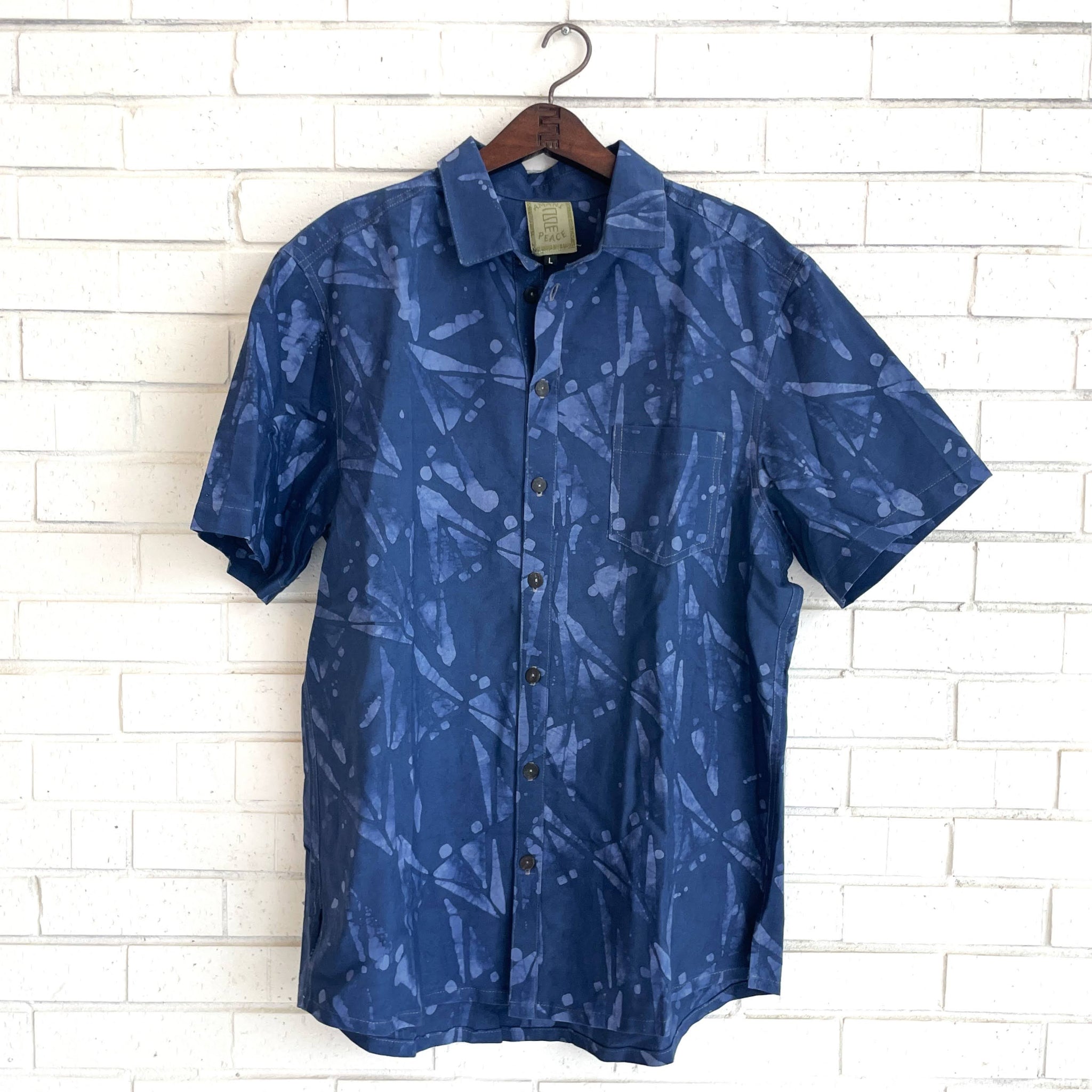 Blue patterned shirt on a hanger against a white brick wall