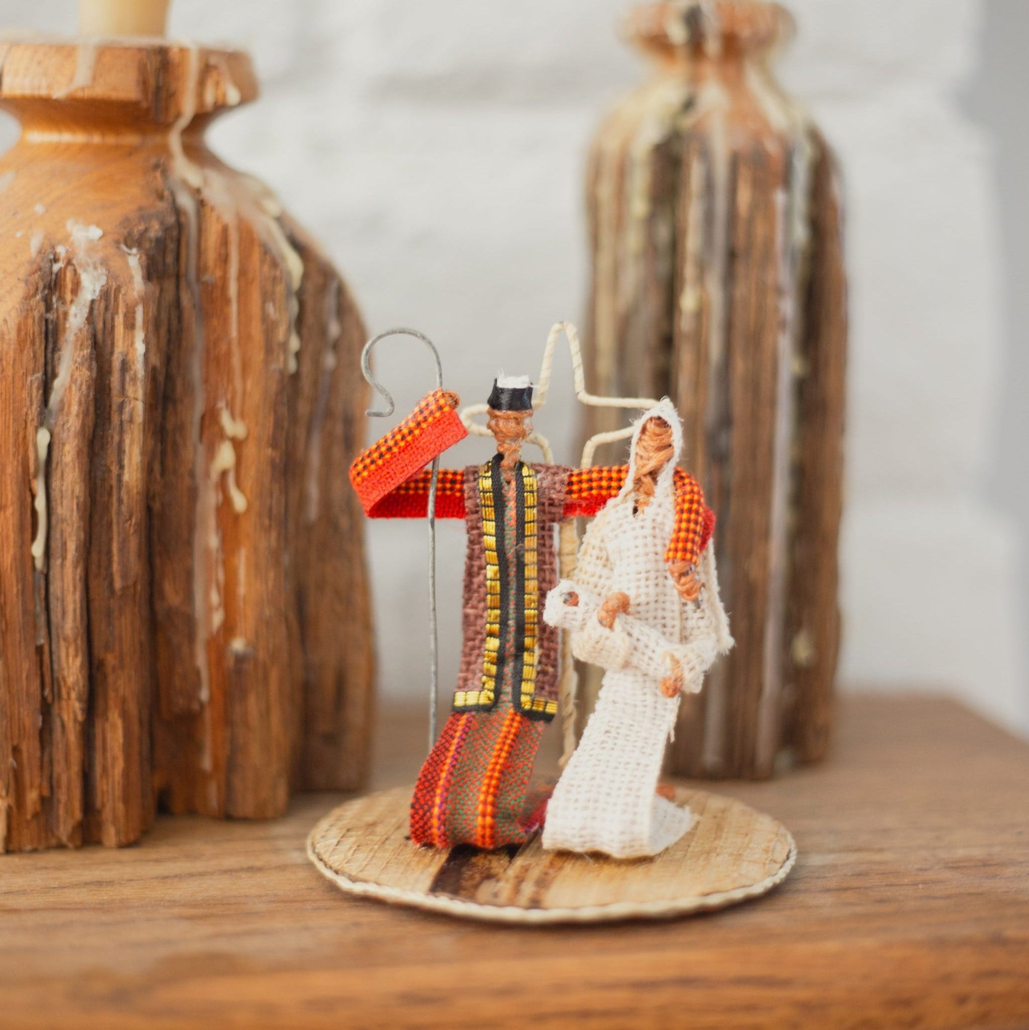 Simple nativity set with Mary, Joseph, and baby Jesus on a wooden surface with decorative elements.