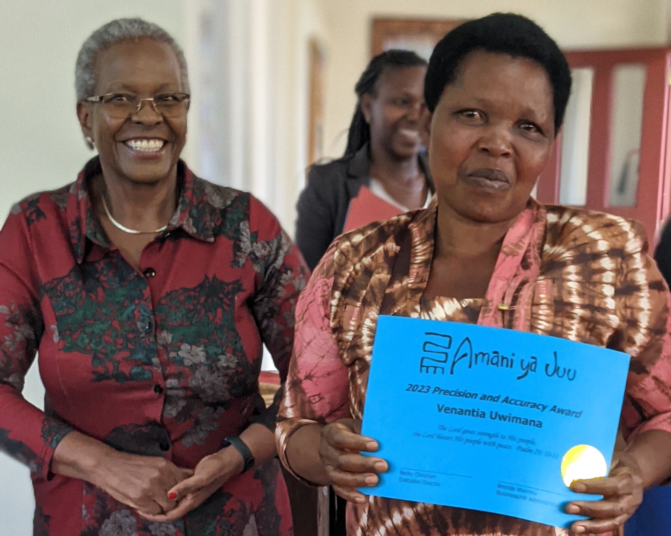Two women holding a blue certificate indoors.