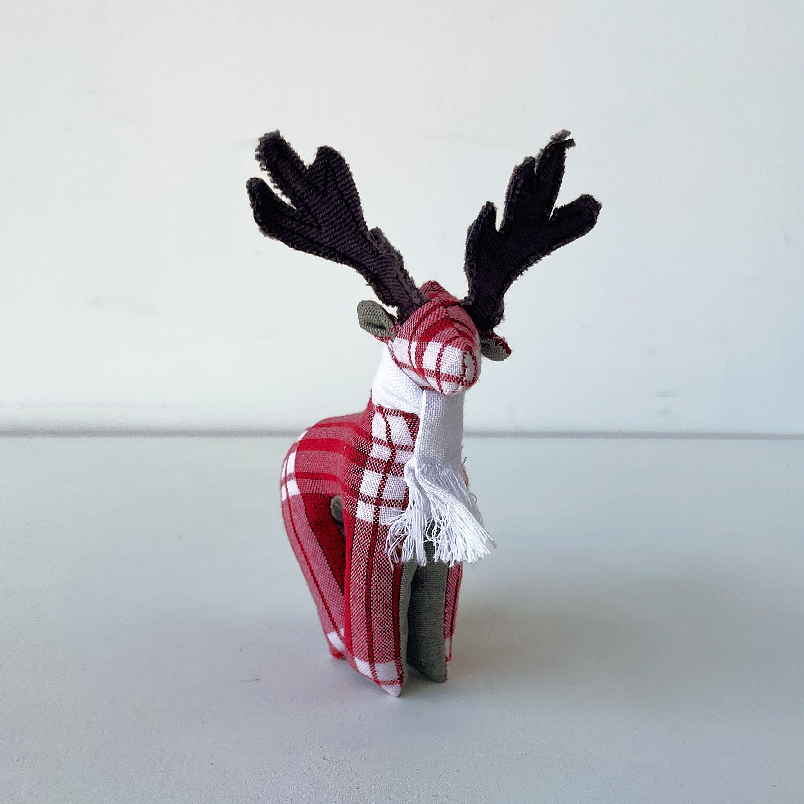 Toy reindeer with plaid pattern and scarf on a white background