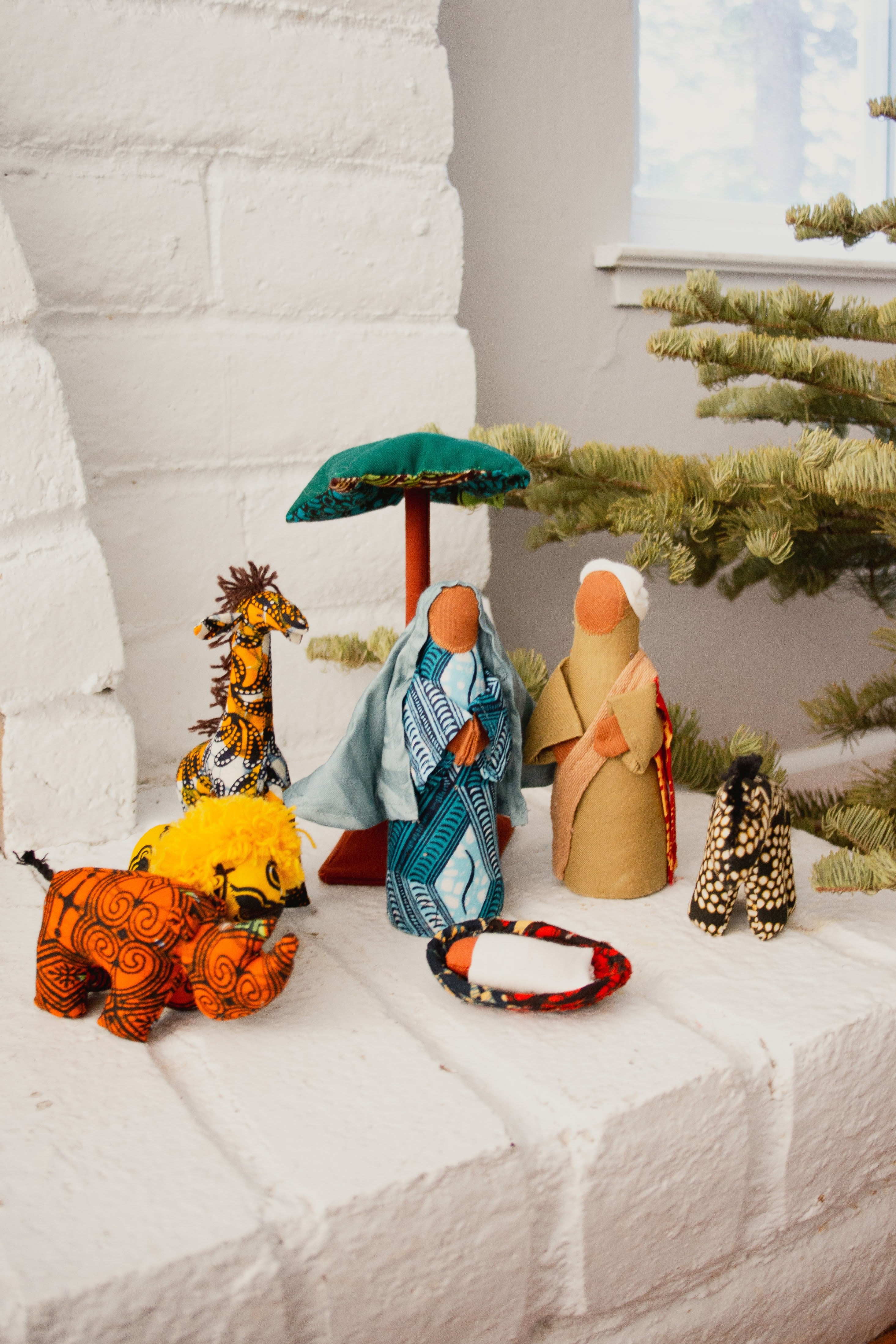 Nativity scene with figurines on a white fireplace.