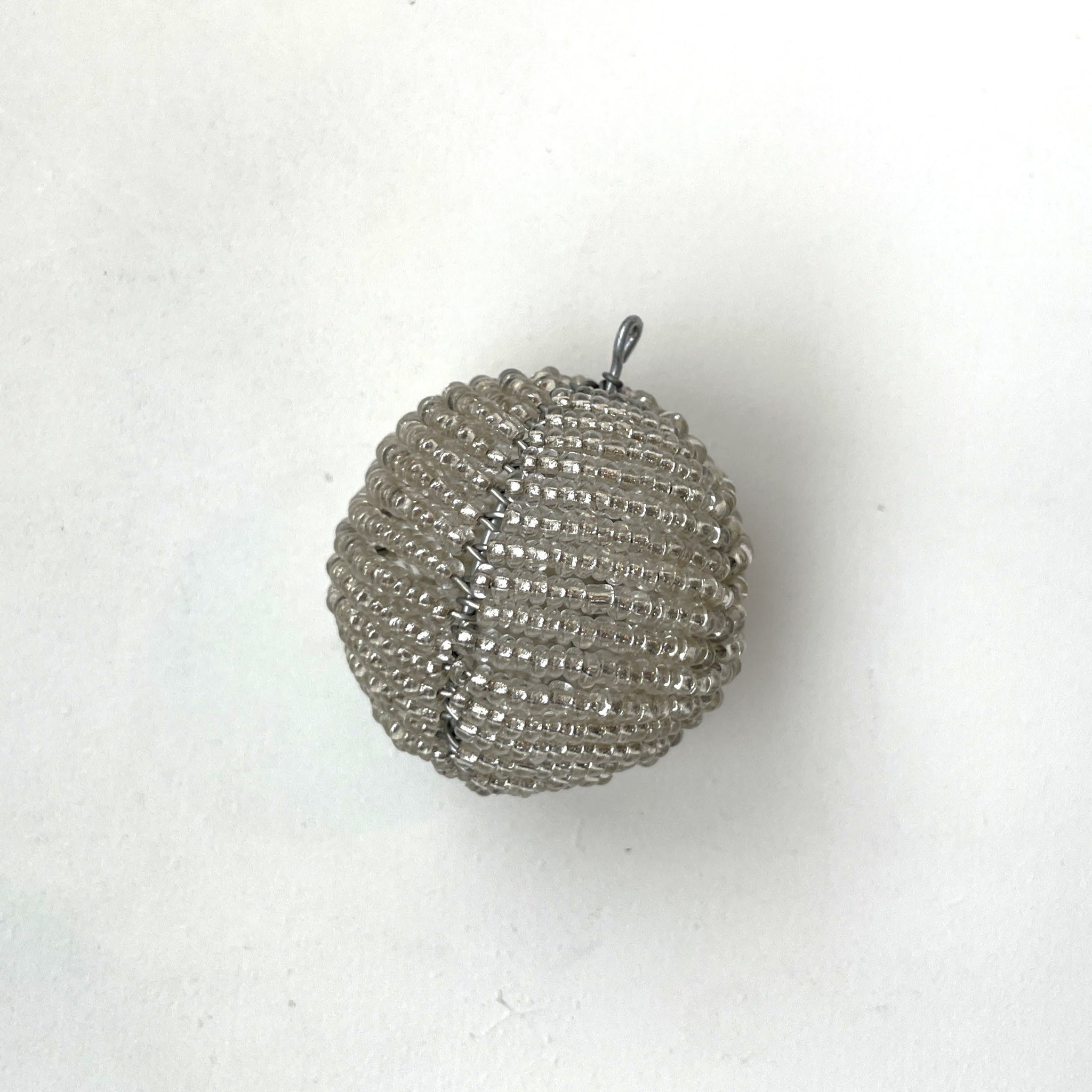 Silver beaded ball ornament on a white background