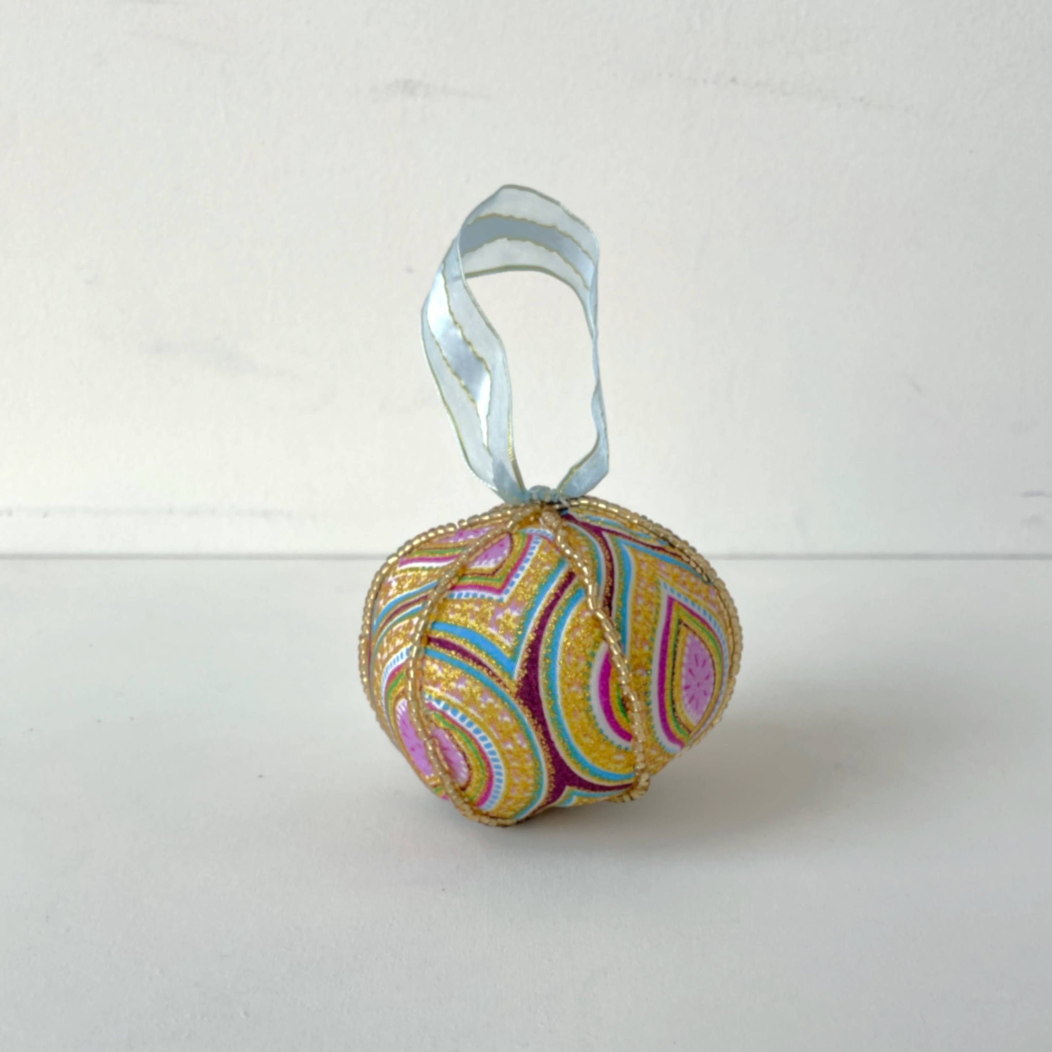 Decorative ball ornament with a ribbon on a white background