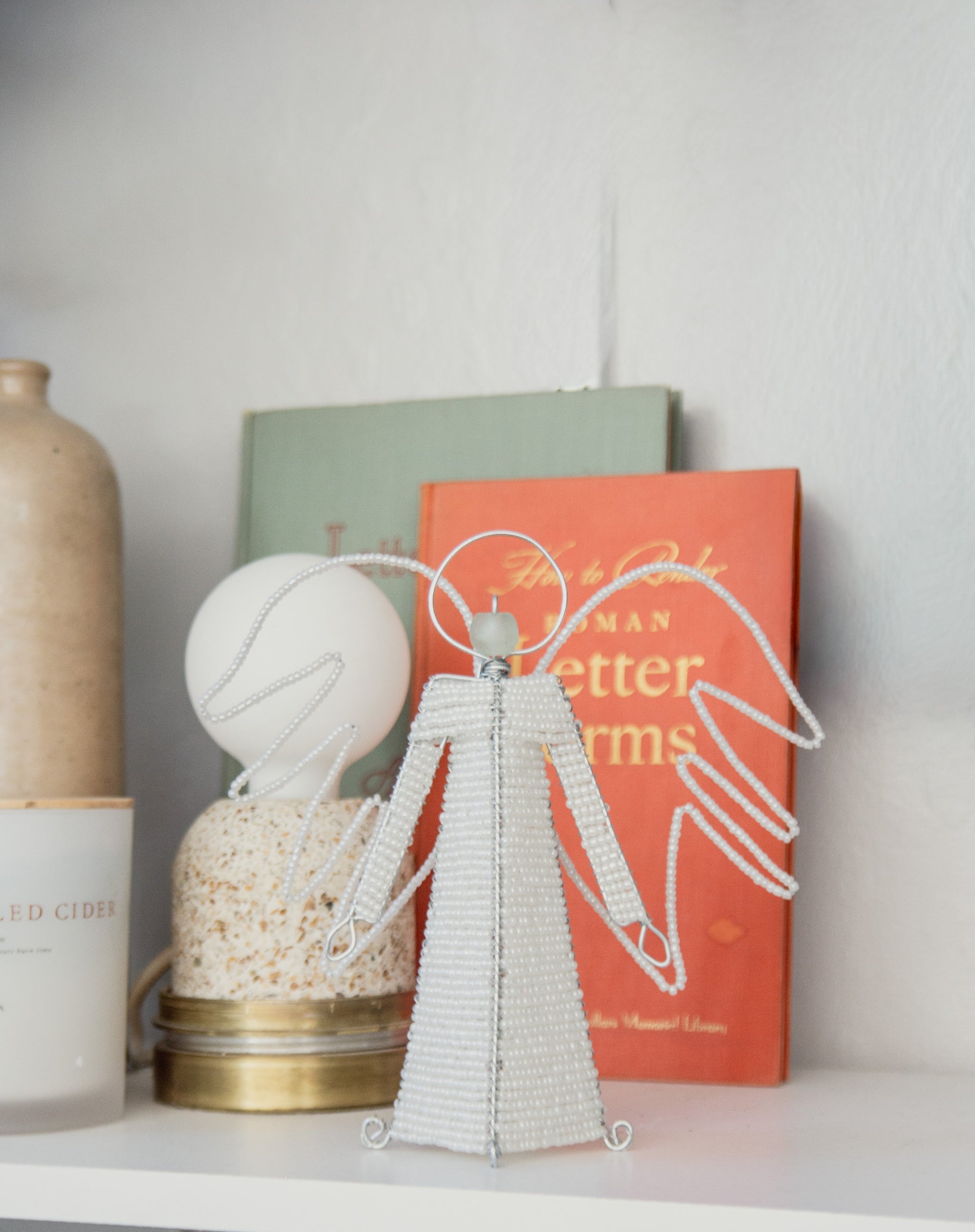 Decorative angel figure on a shelf with books and a vase