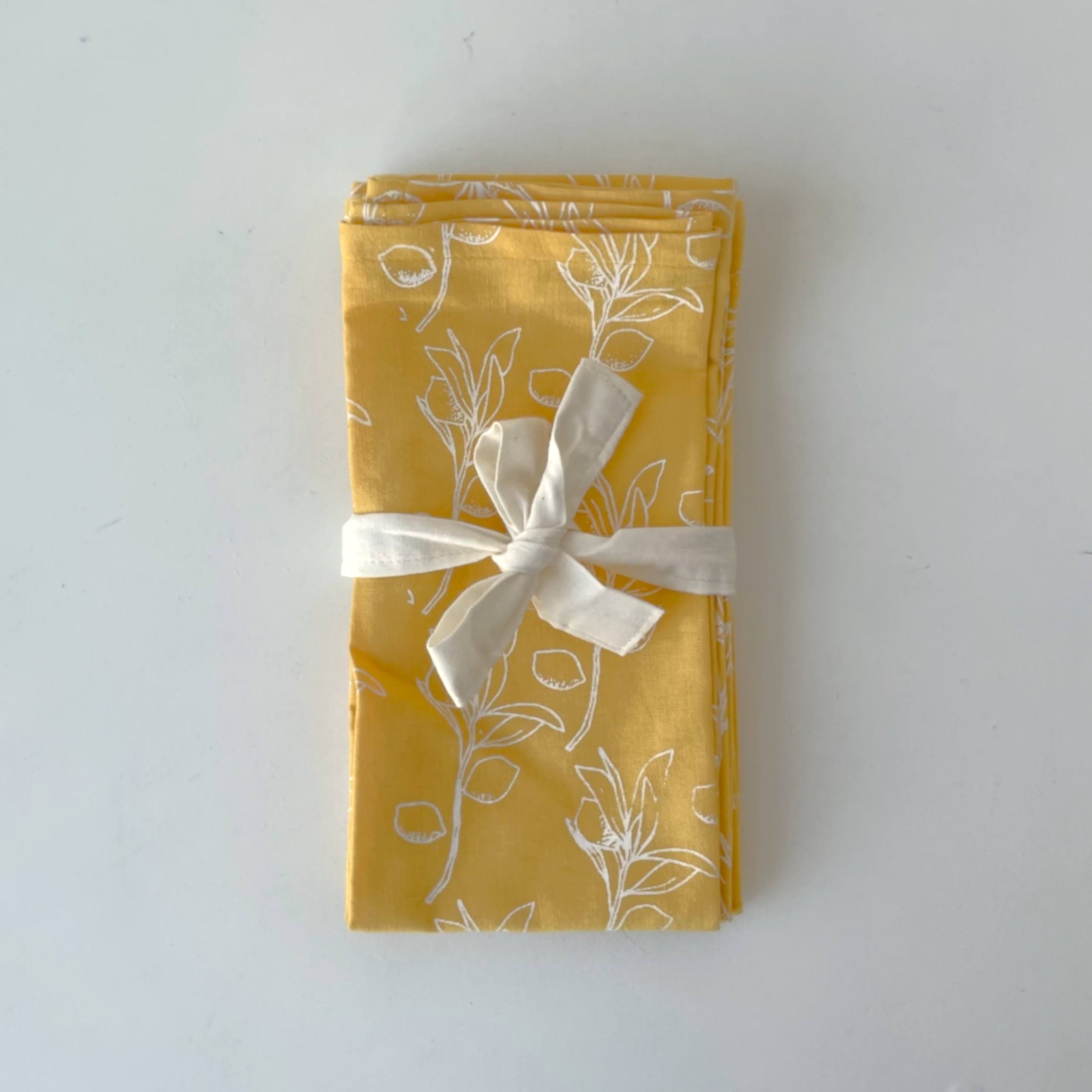 Yellow fabric with white fruit pattern and a white ribbon on a white background