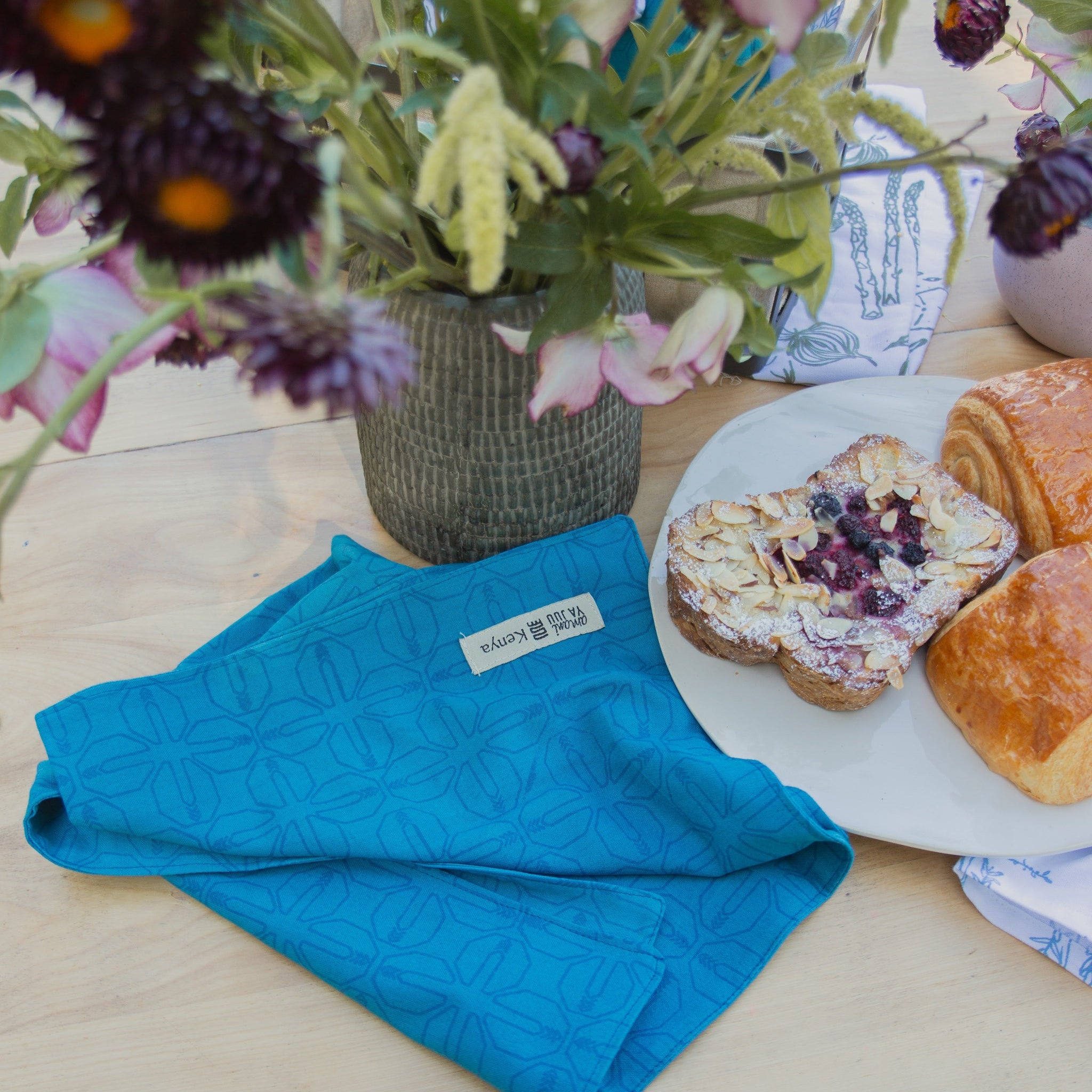 Blue towel with a brand label on a table with bread and flowers