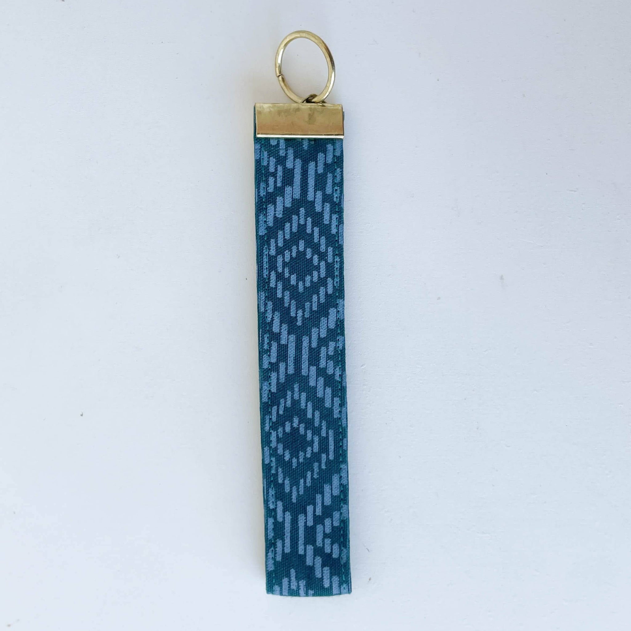 Blue patterned keychain with gold ring on a white background