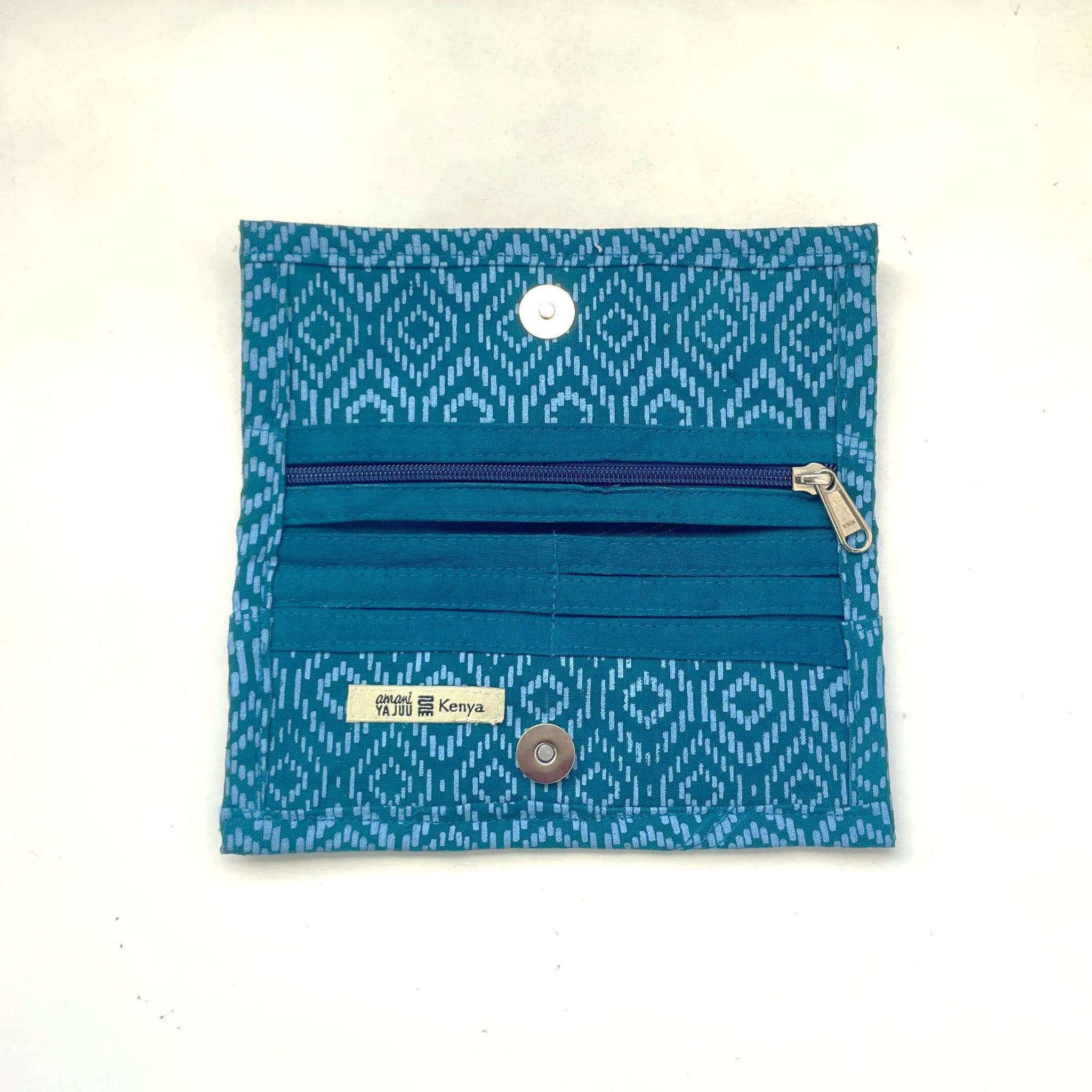 A small fabric zippered wallet in teal and blue patterned material, shown flat against a light off-white background. It has a top zipper, multiple horizontal card slots and snap buttons.