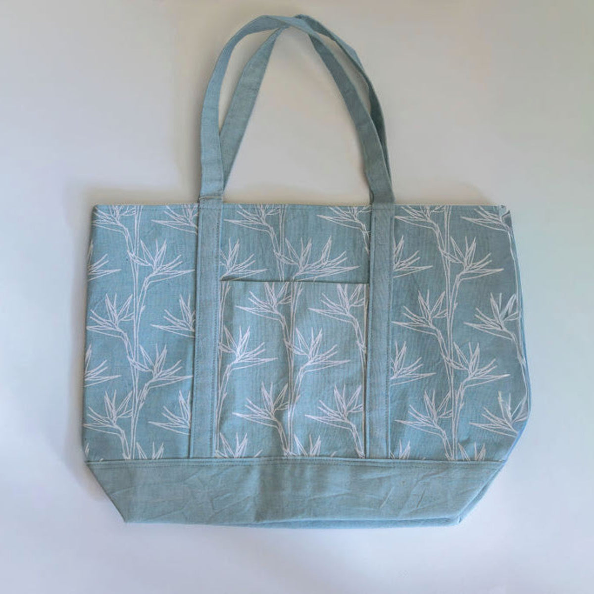 Light blue green tote bag with floral pattern on white background