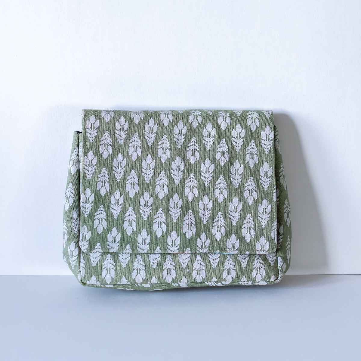 Moss green crossbody bag with floral pattern on light background