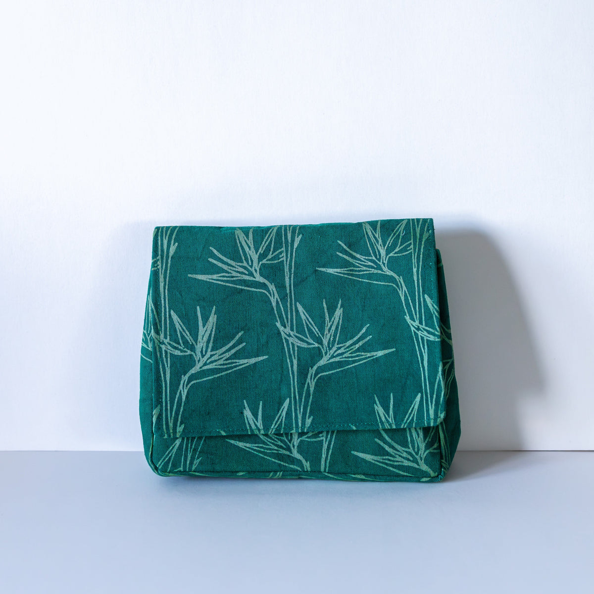 Emerald green crossbody bag with floral pattern on light background