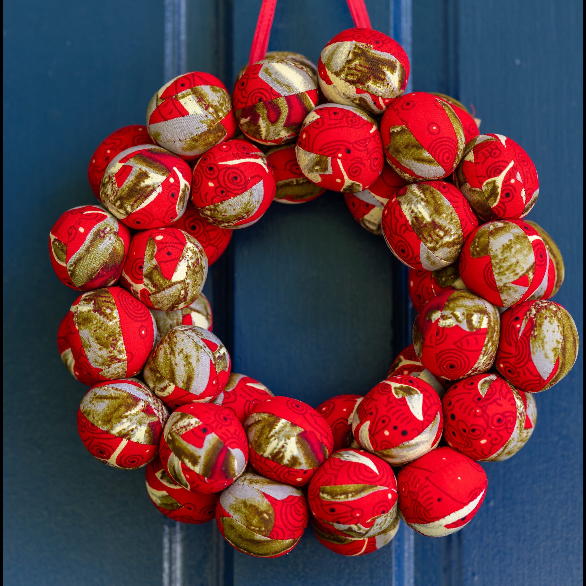 Red and gold fabric ball wreath on blue door