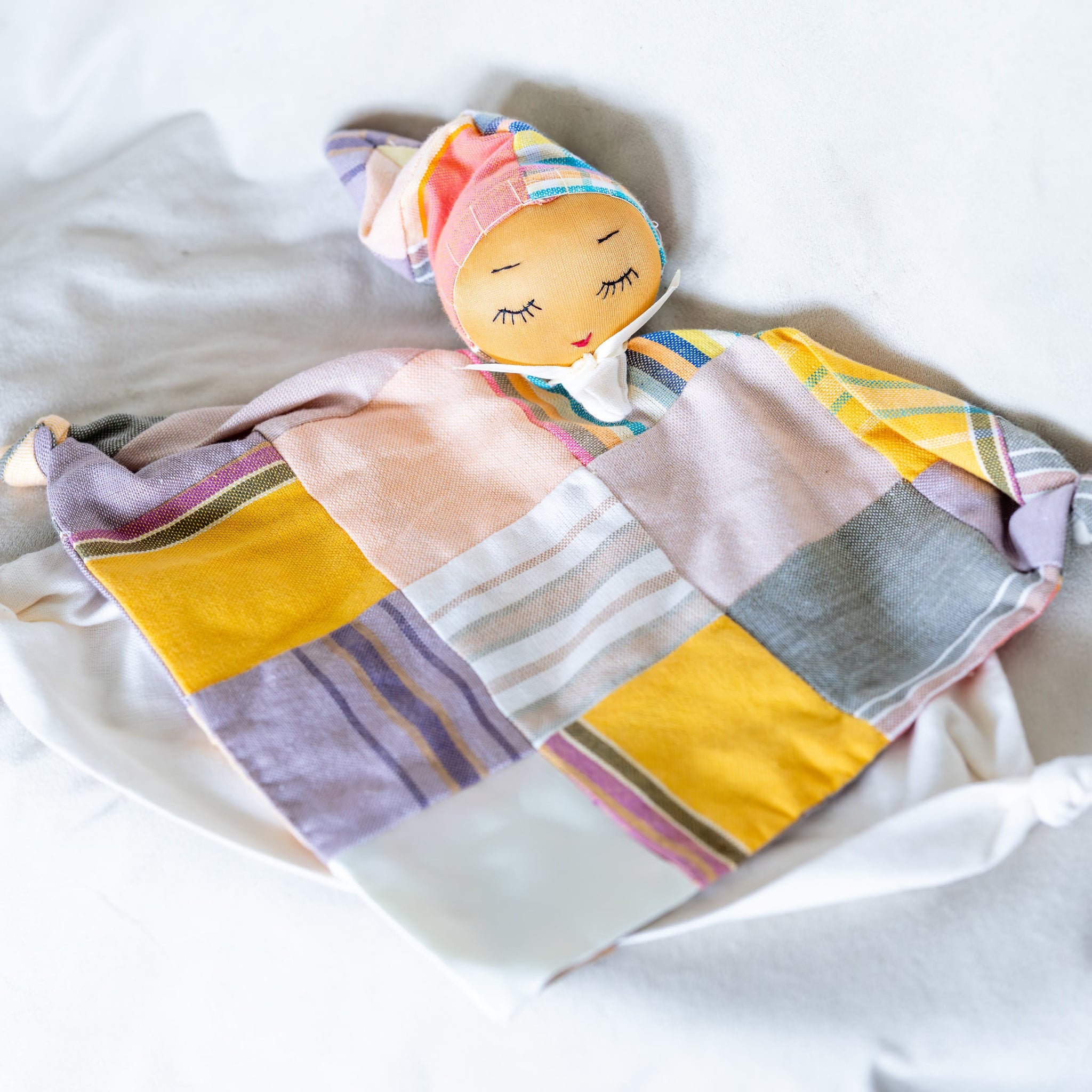 Soft doll with patchwork clothing on white background