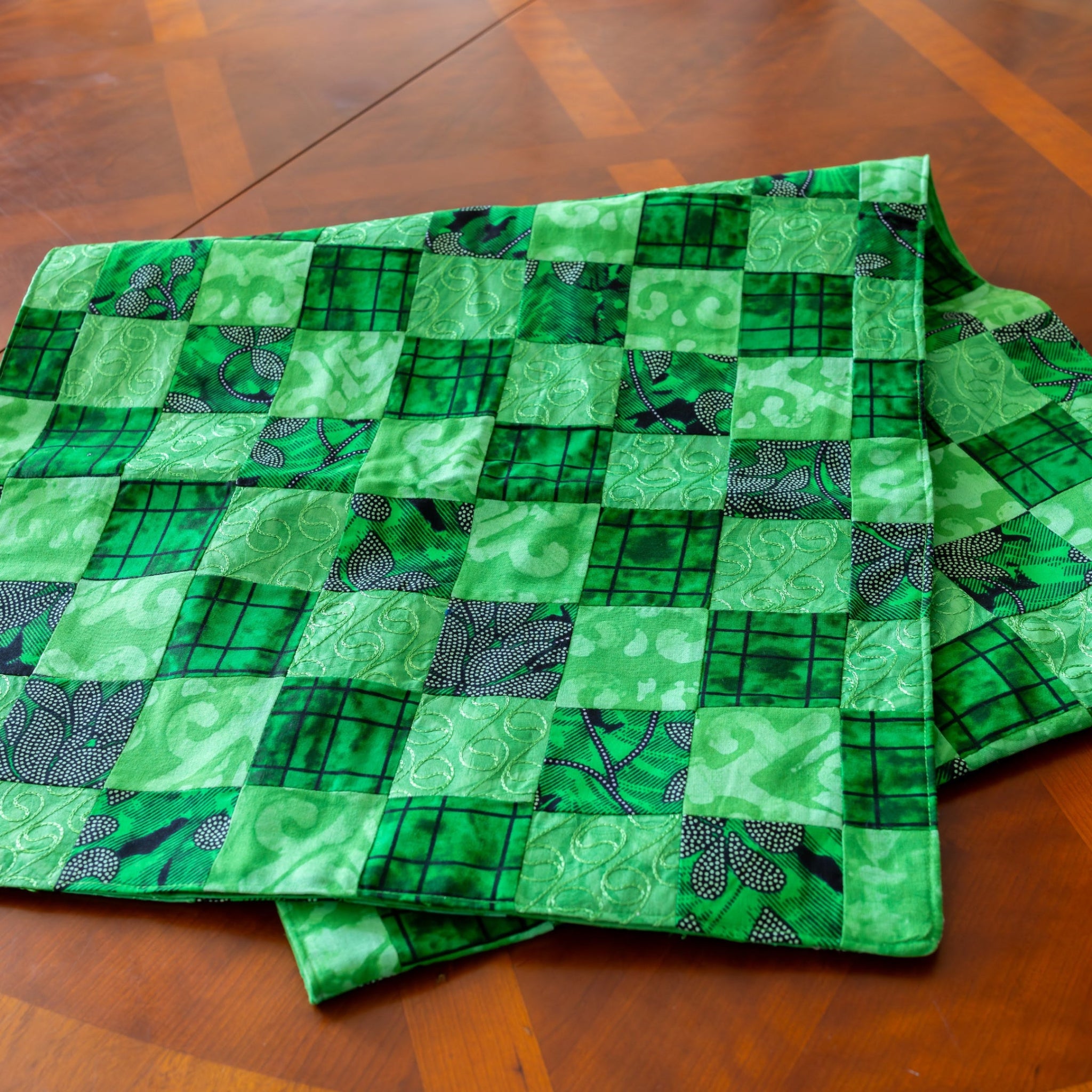Folded green patchwork table runner on wooden table