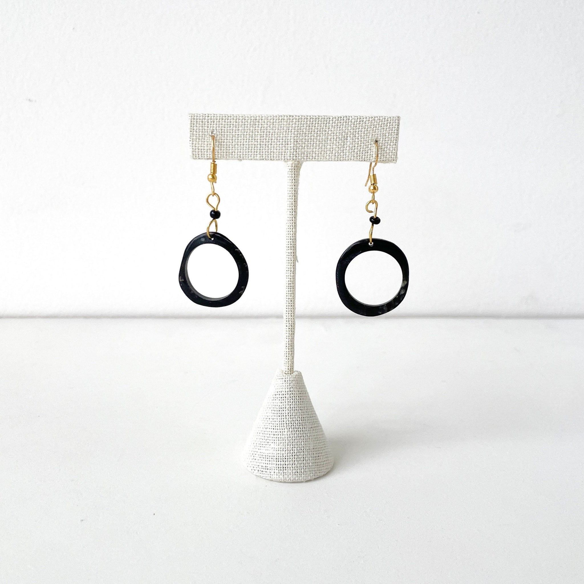 Black hoop earrings on a white stand against a white background