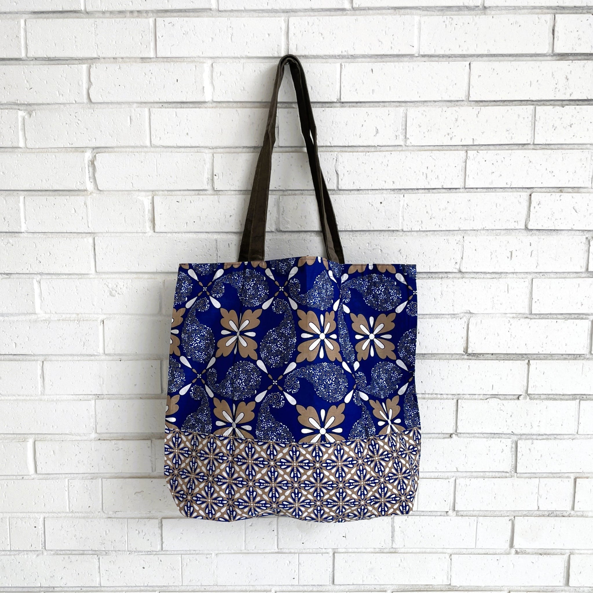 Tote bag with blue and brown pattern against a white brick wall