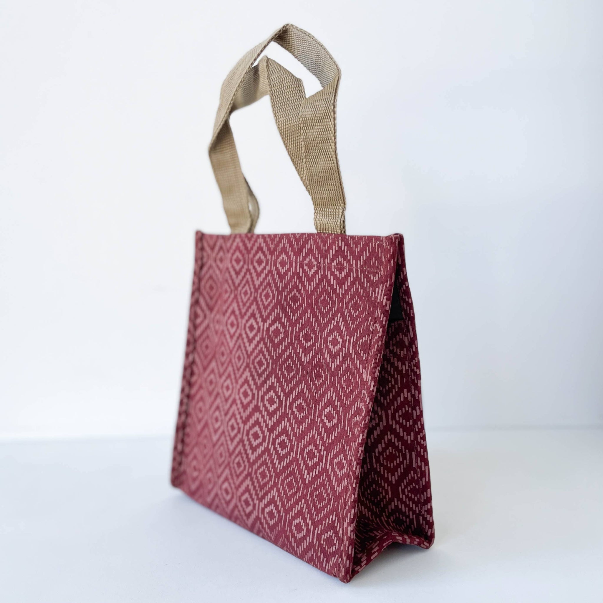 Red patterned tote bag with a beige handle on a white background