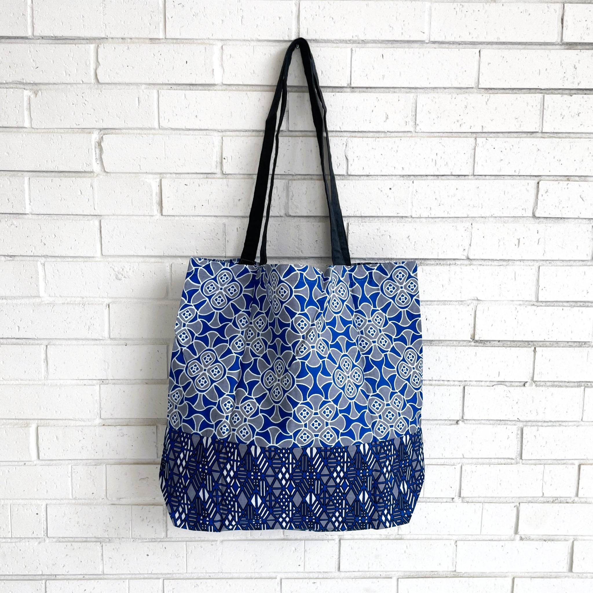 Tote bag with blue and white pattern against a white brick wall