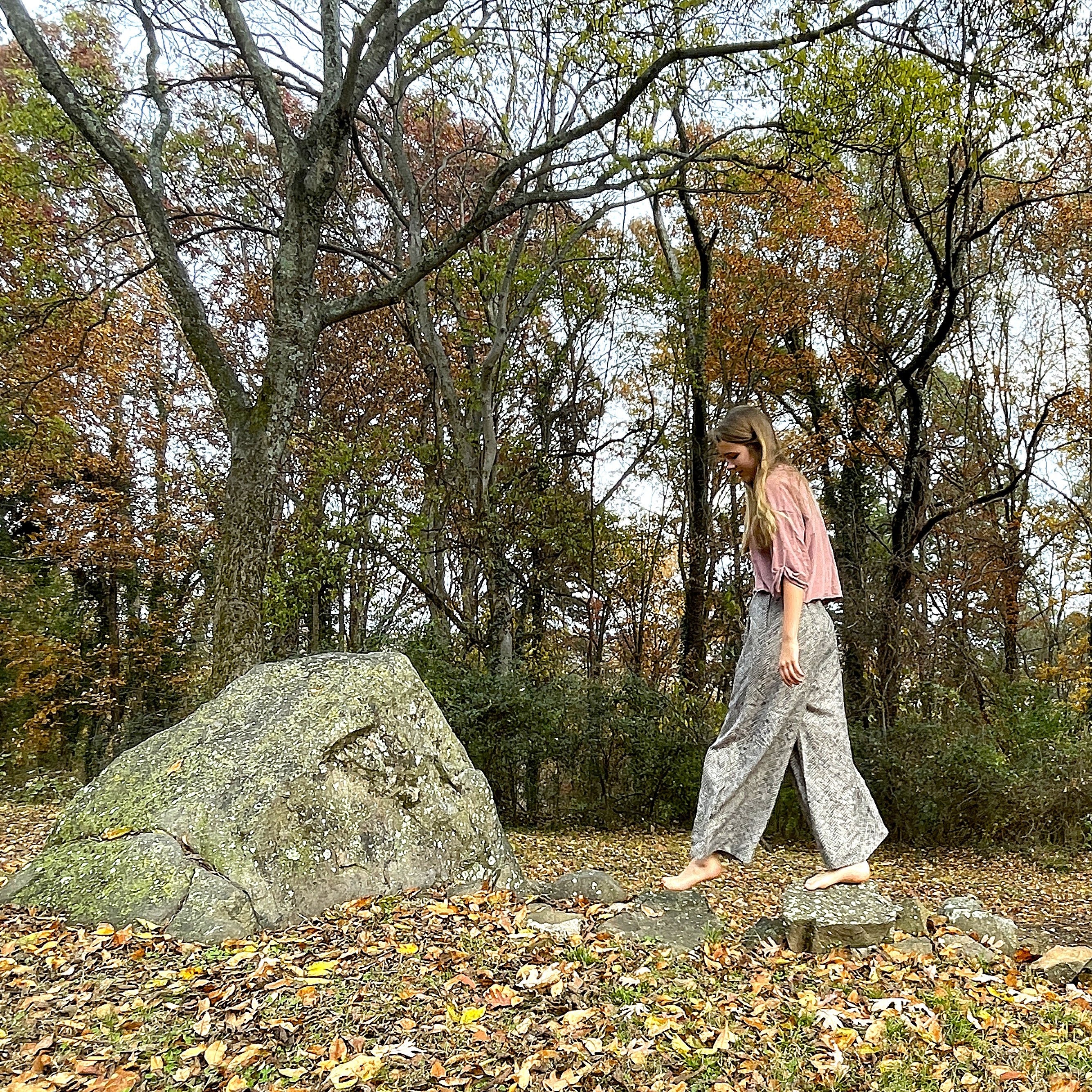 Person walking in a forest with trees and rocks