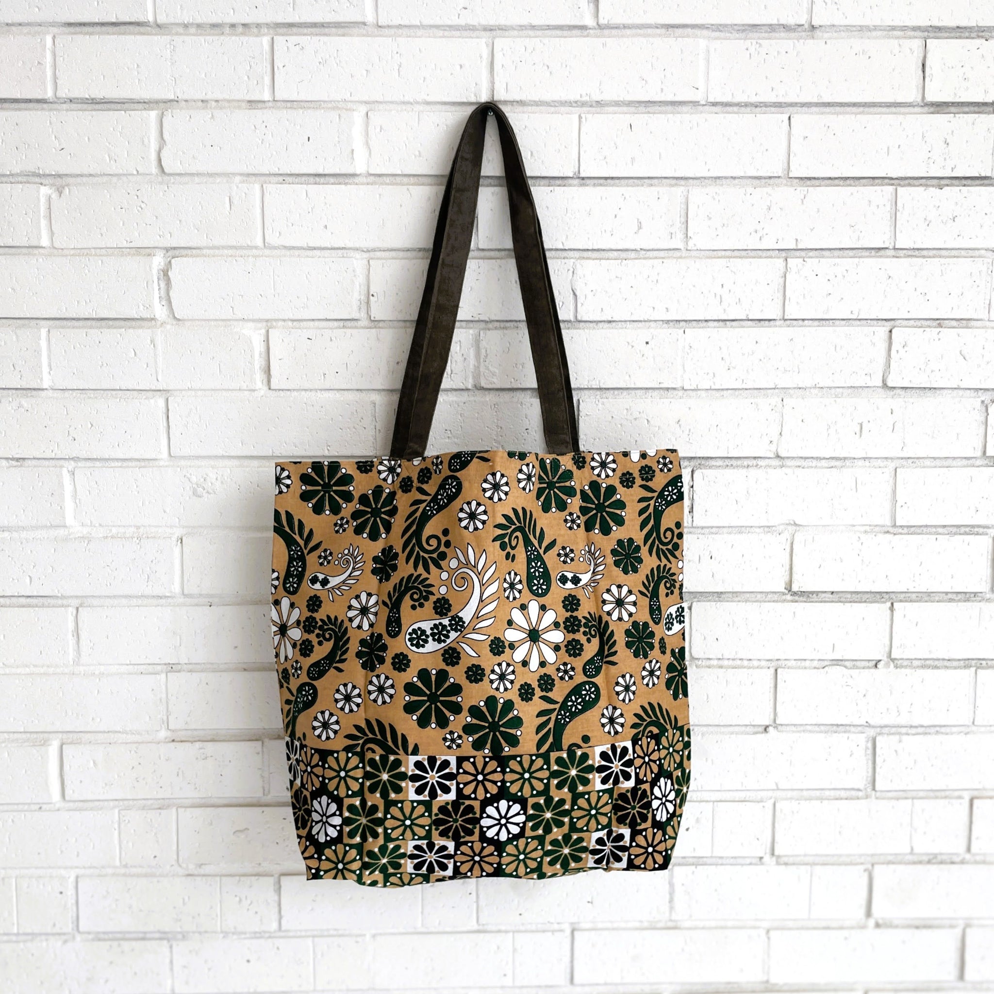 Tote bag with floral pattern against a white brick wall