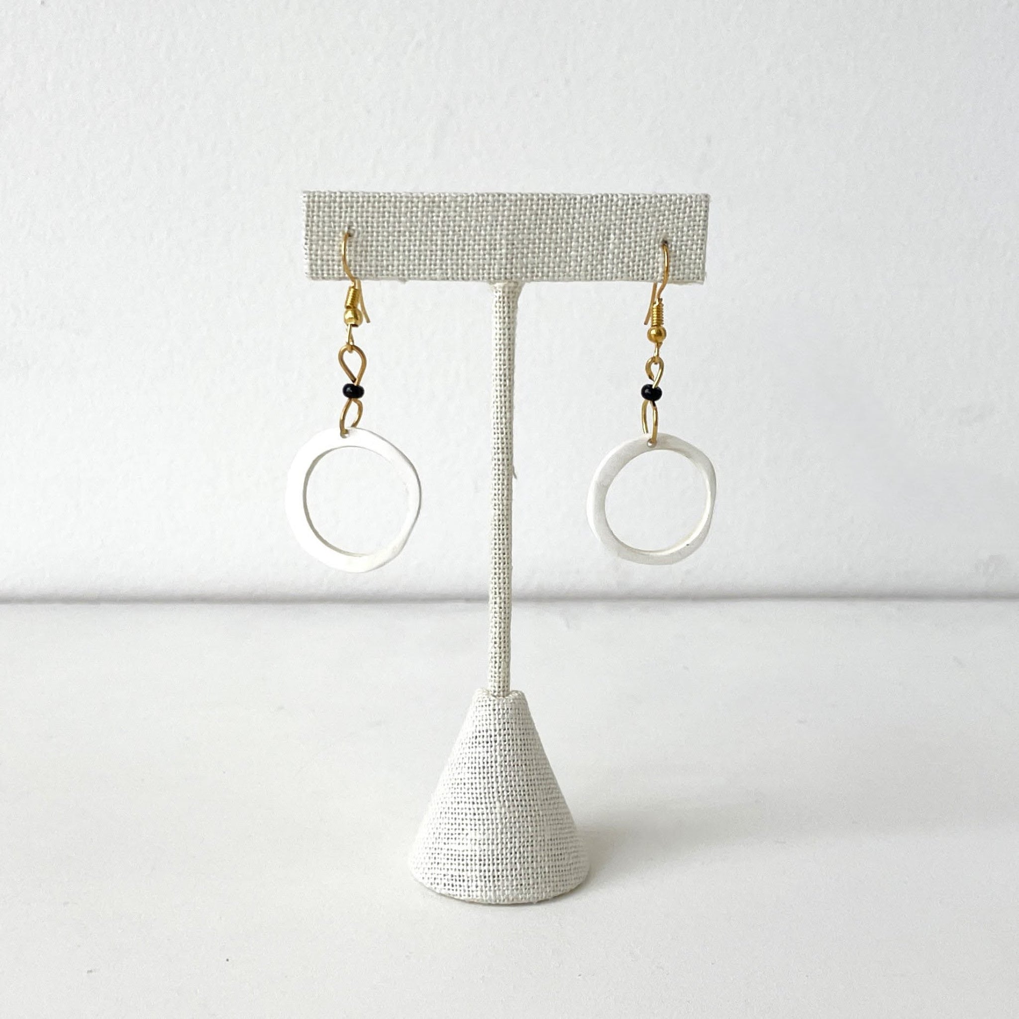 Pair of earrings on a textured stand against a white background