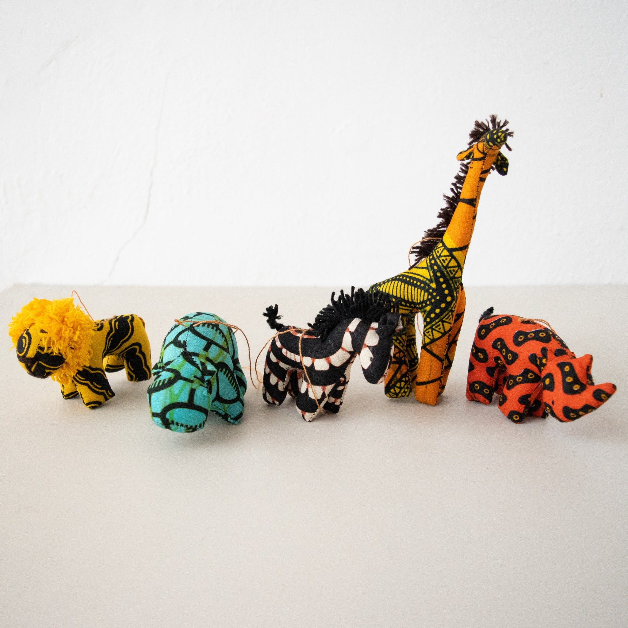 A set of handcrafted plush animal ornaments in various colors and patterns, designed to resemble giraffes, zebras, and a zebra.
