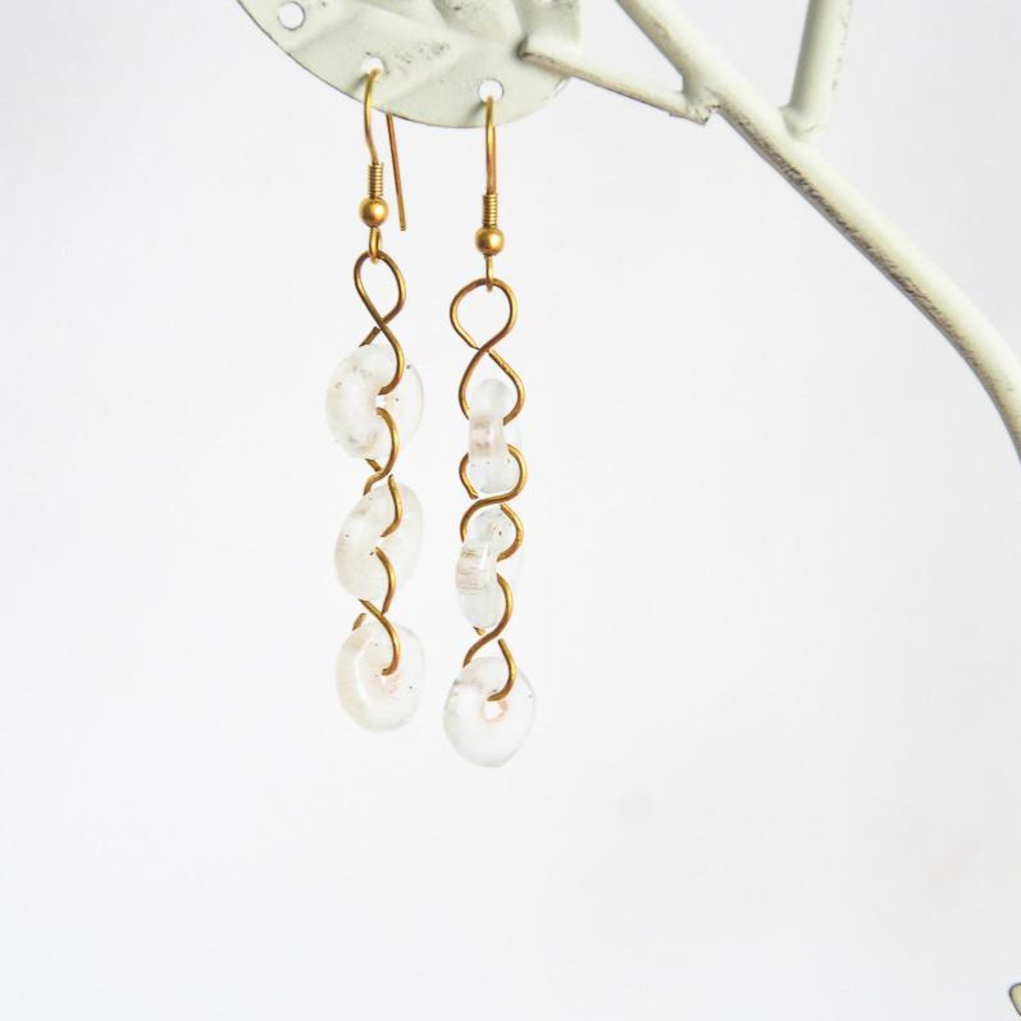 A pair of dangle earrings made with white glass beads and gold-colored metal, displayed against a light background.